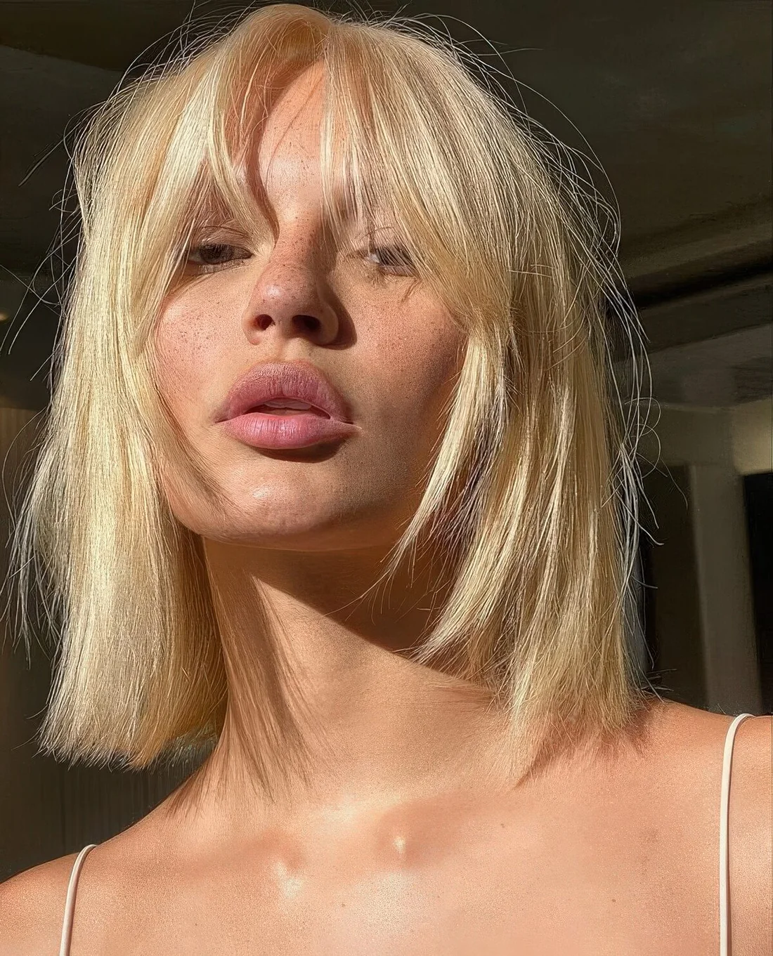 Long blonde bob with layers and bottleneck bangs.