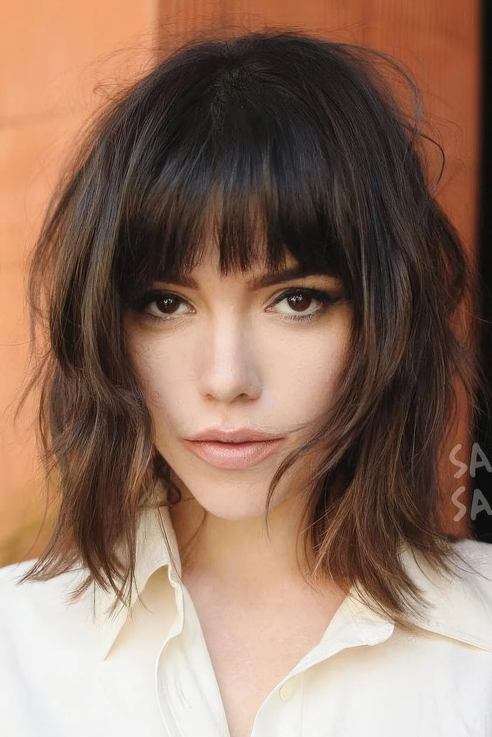 Dark brown long shaggy bob with caramel highlights and a classic fringe plus messy waves.