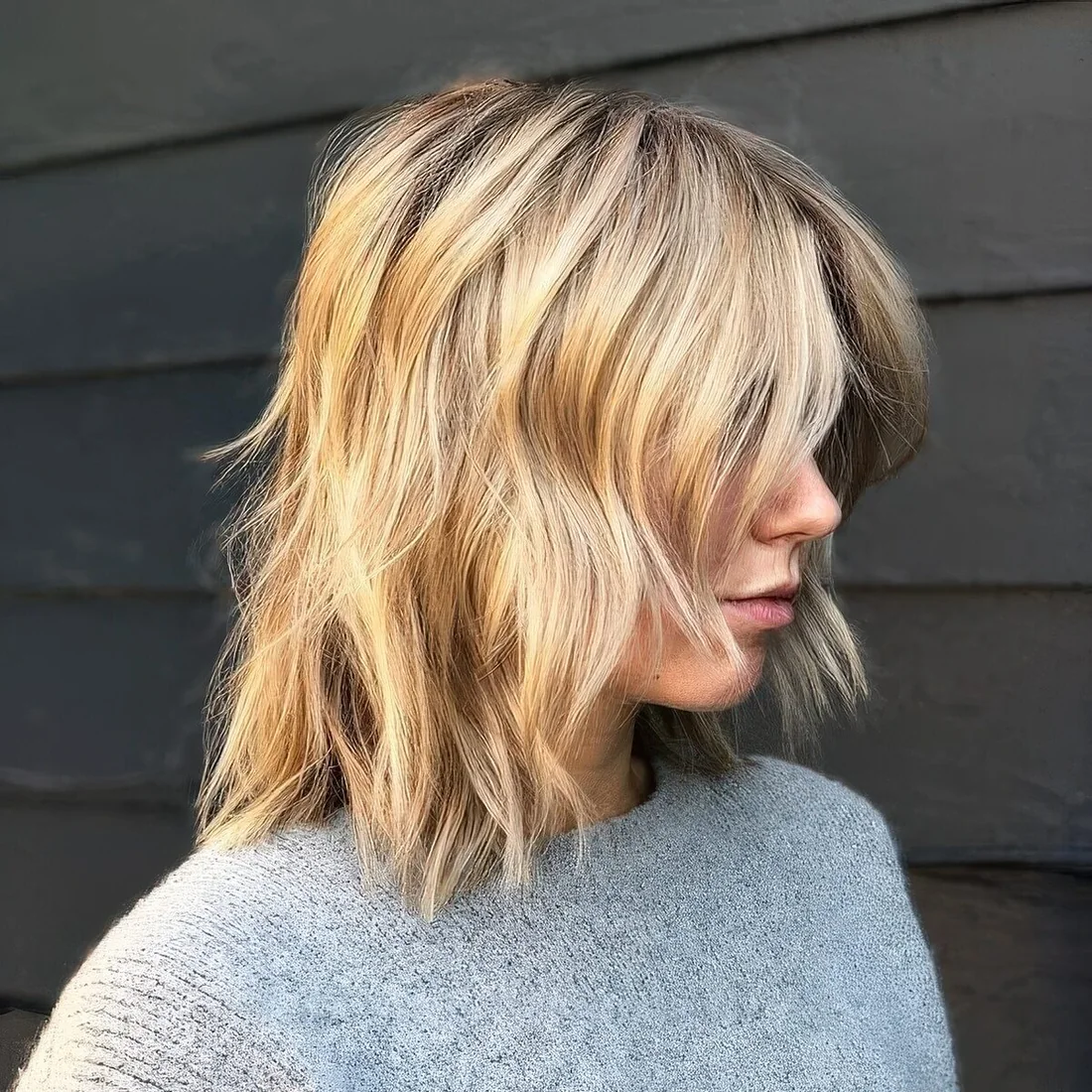 Messy blonde wavy long bob with curtain bangs.