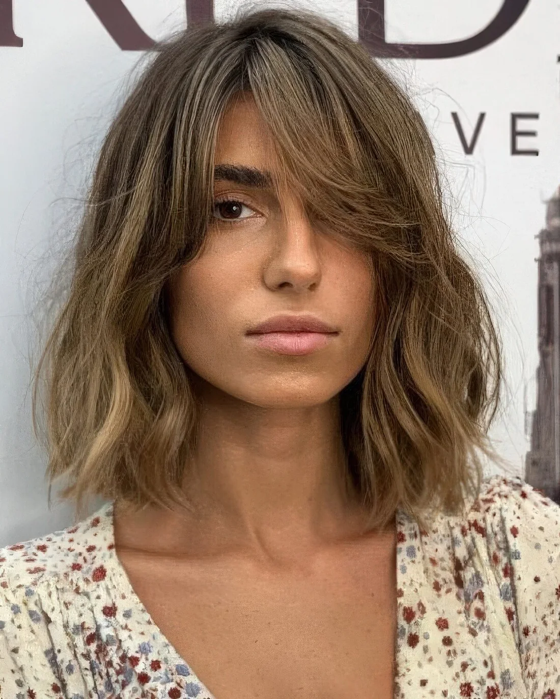 Messy bronde long bob with a darker root and waves plus curtain bangs to soft the look even more.