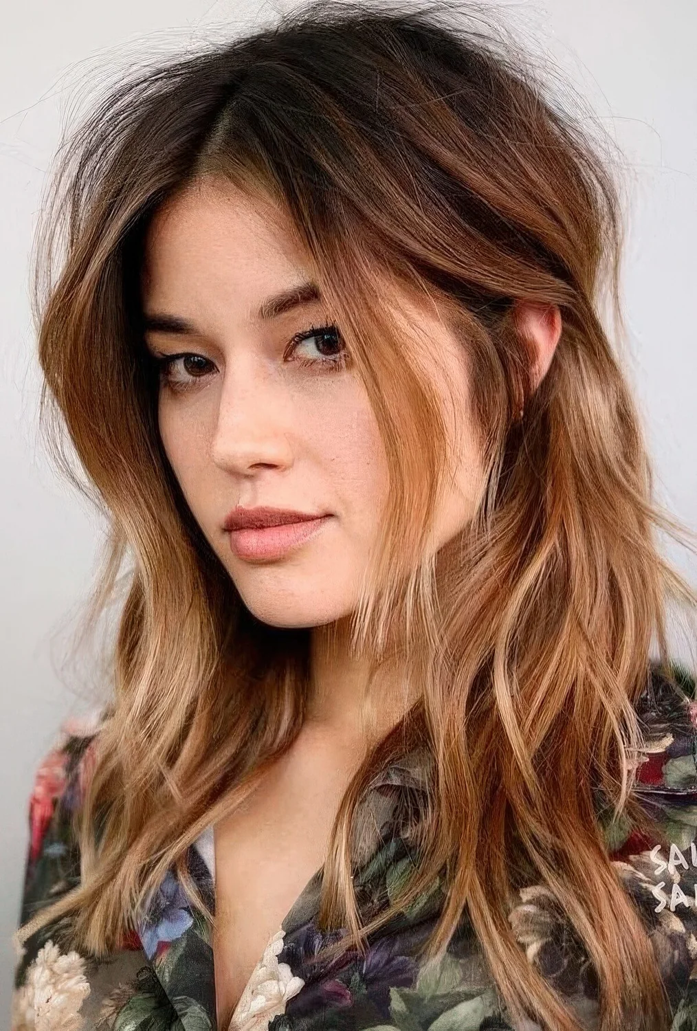 Dark brown root plus ombre caramel ends and messy waves plus layered bangs.