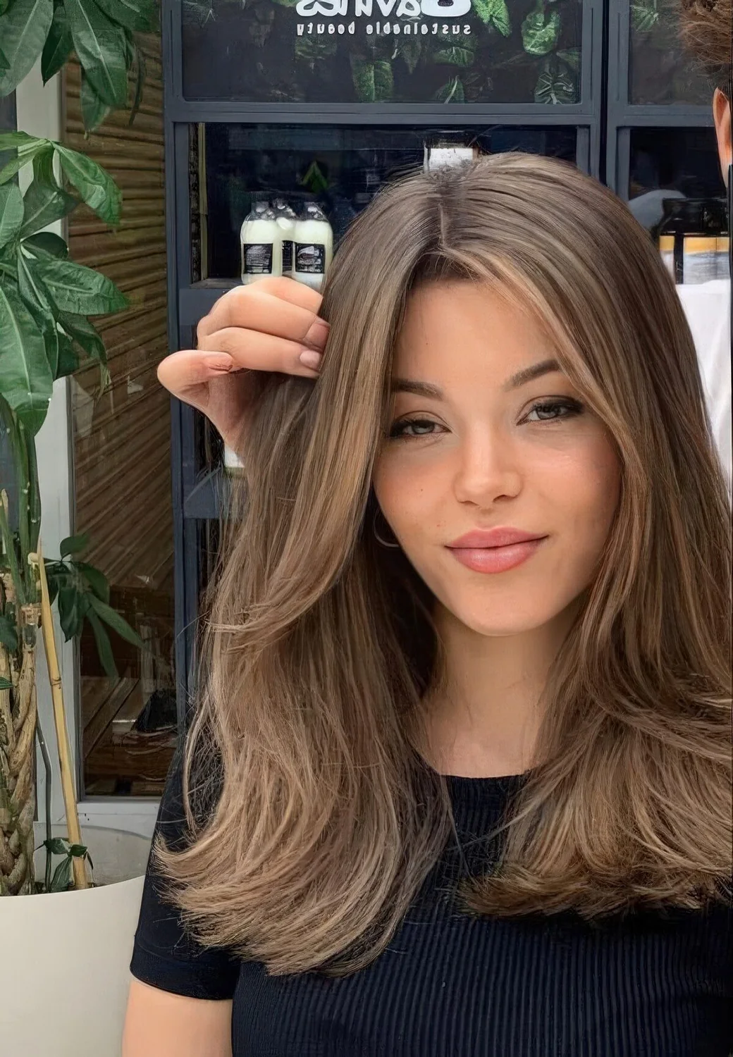 Long brunette hair with caramel highlights and chin bangs.