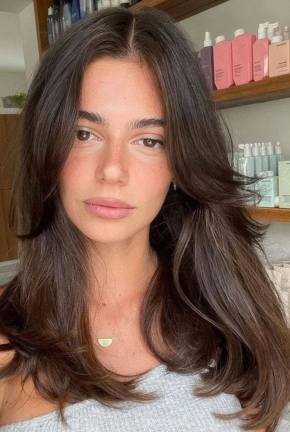 Long dark brown hair with curtain bangs and center part.