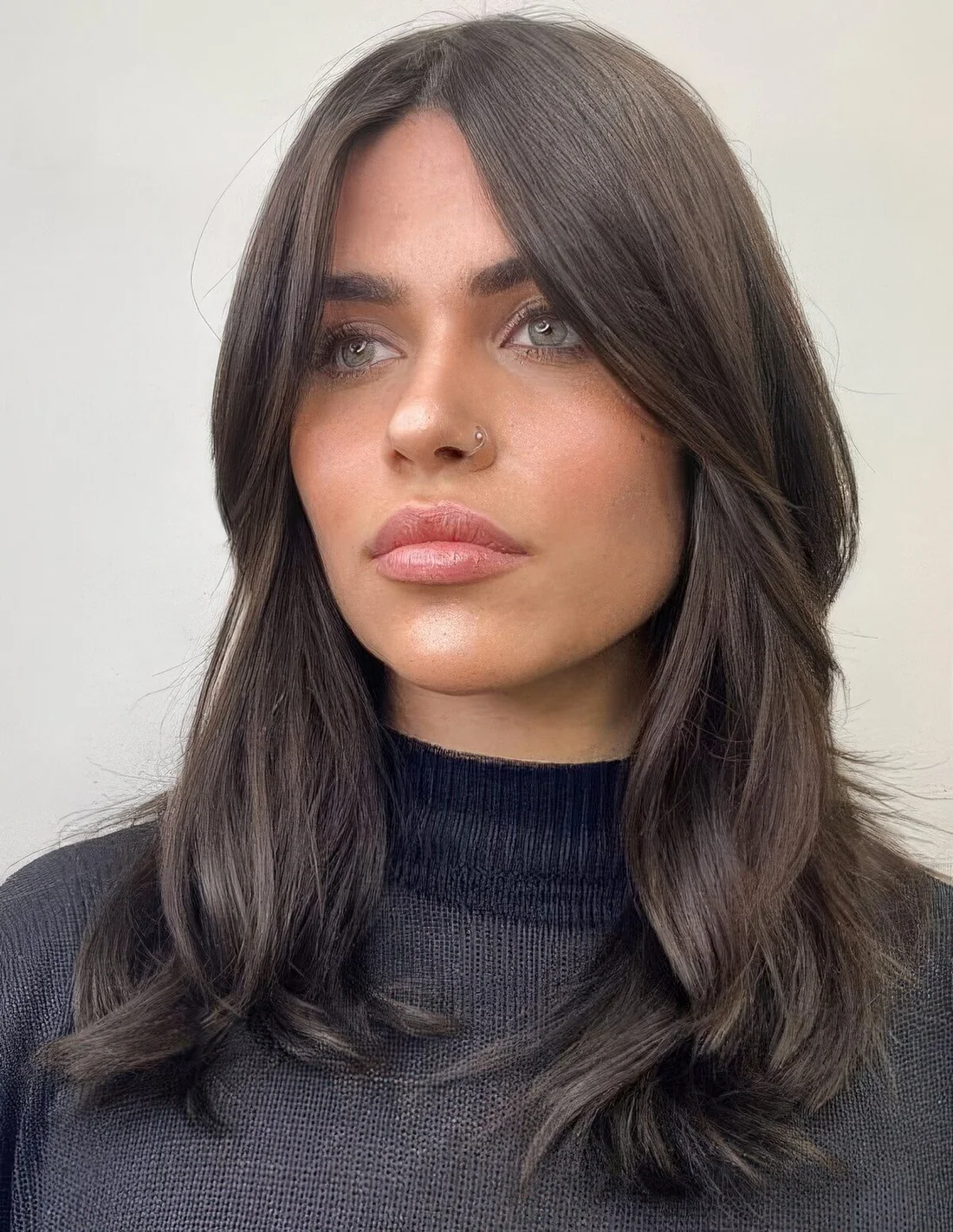 Medium-length dark brown hair with chin bangs and waves, middle part.