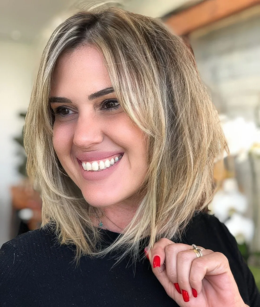 Blonde choppy bob with a darker root, with curtain bangs.