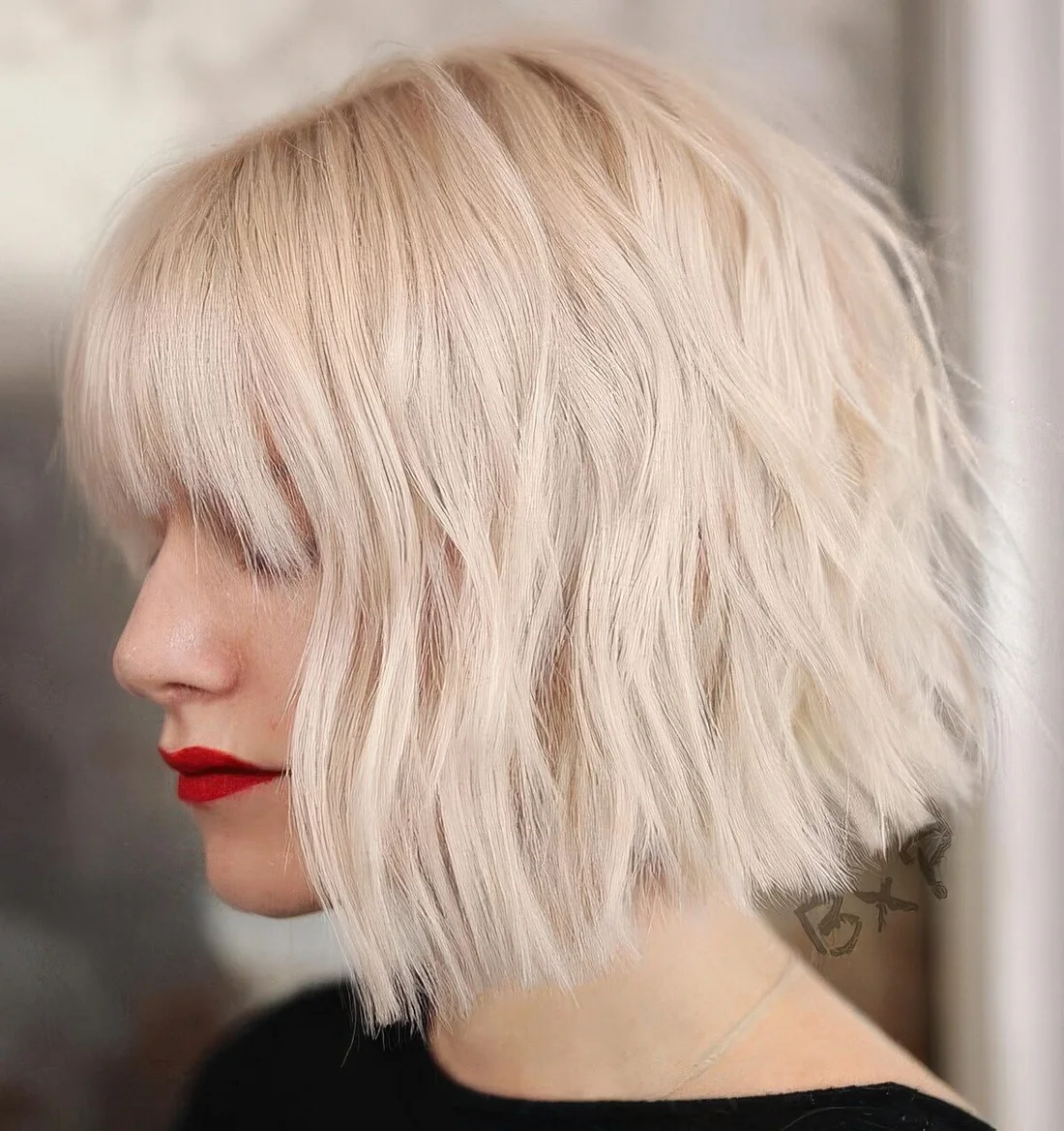 Icy blonde choppy bob with outgrown bangs.