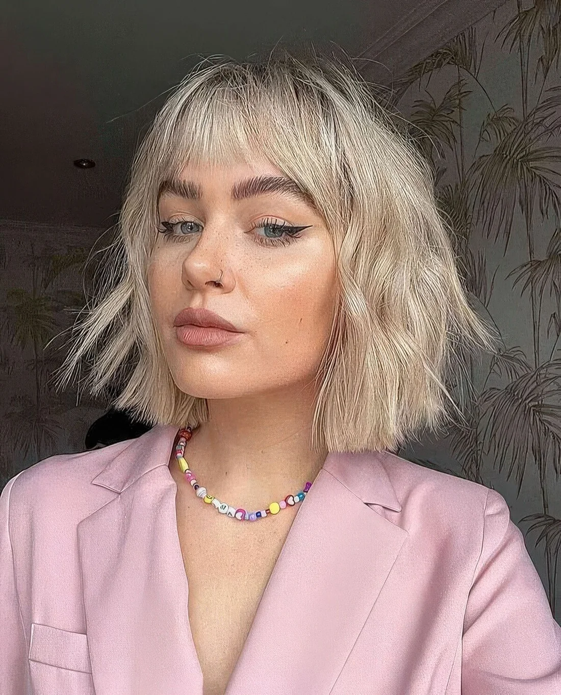 Eye catchy textural and wavy blonde choppy bob with wispy bangs.