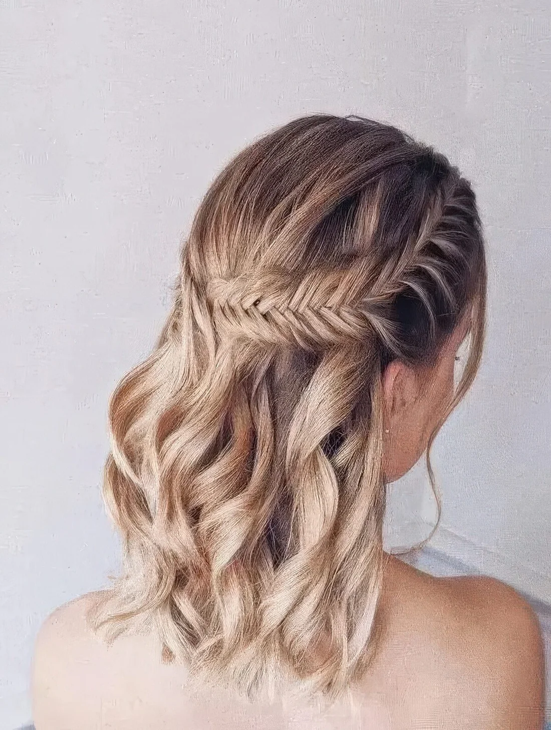 Boho half updo on medium hair, with a large fishtail braid on one side and waves down.