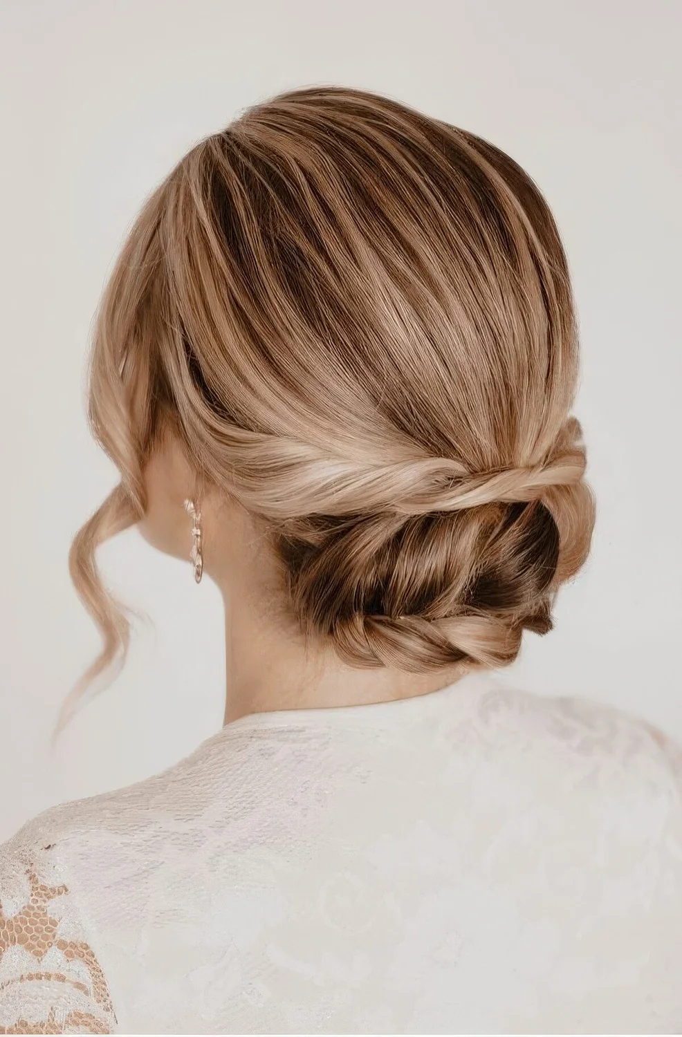 Laconic low updo with twists and a braid and a sleek top, waves framing the face.
