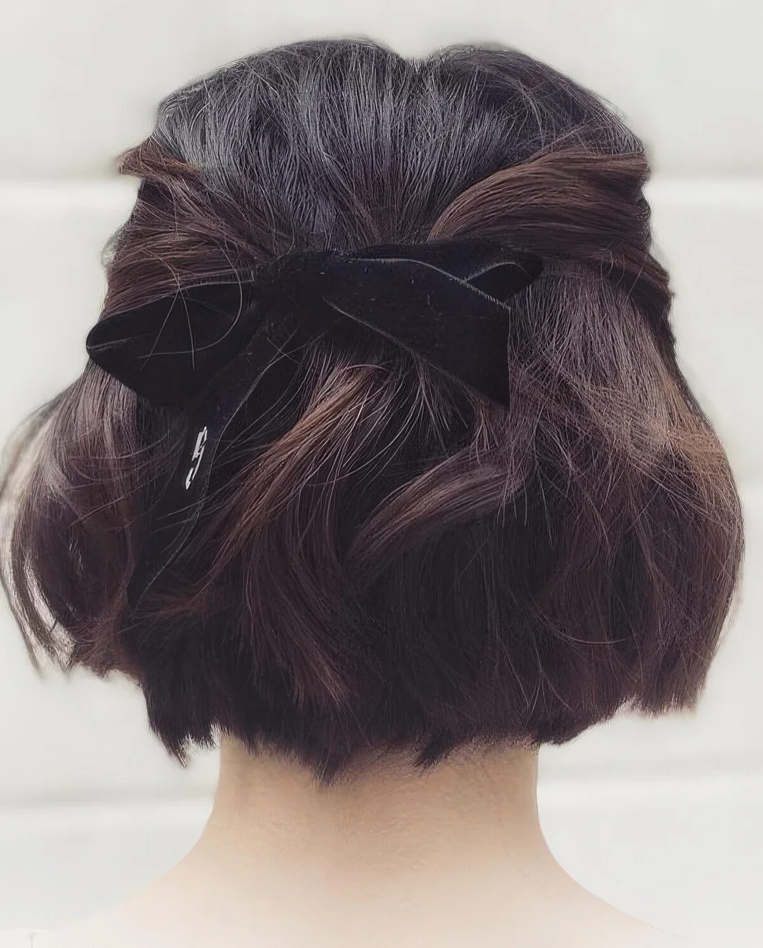 Half updo with twisted touches, a lot of volume and waves, a black velvet ribbon bow.