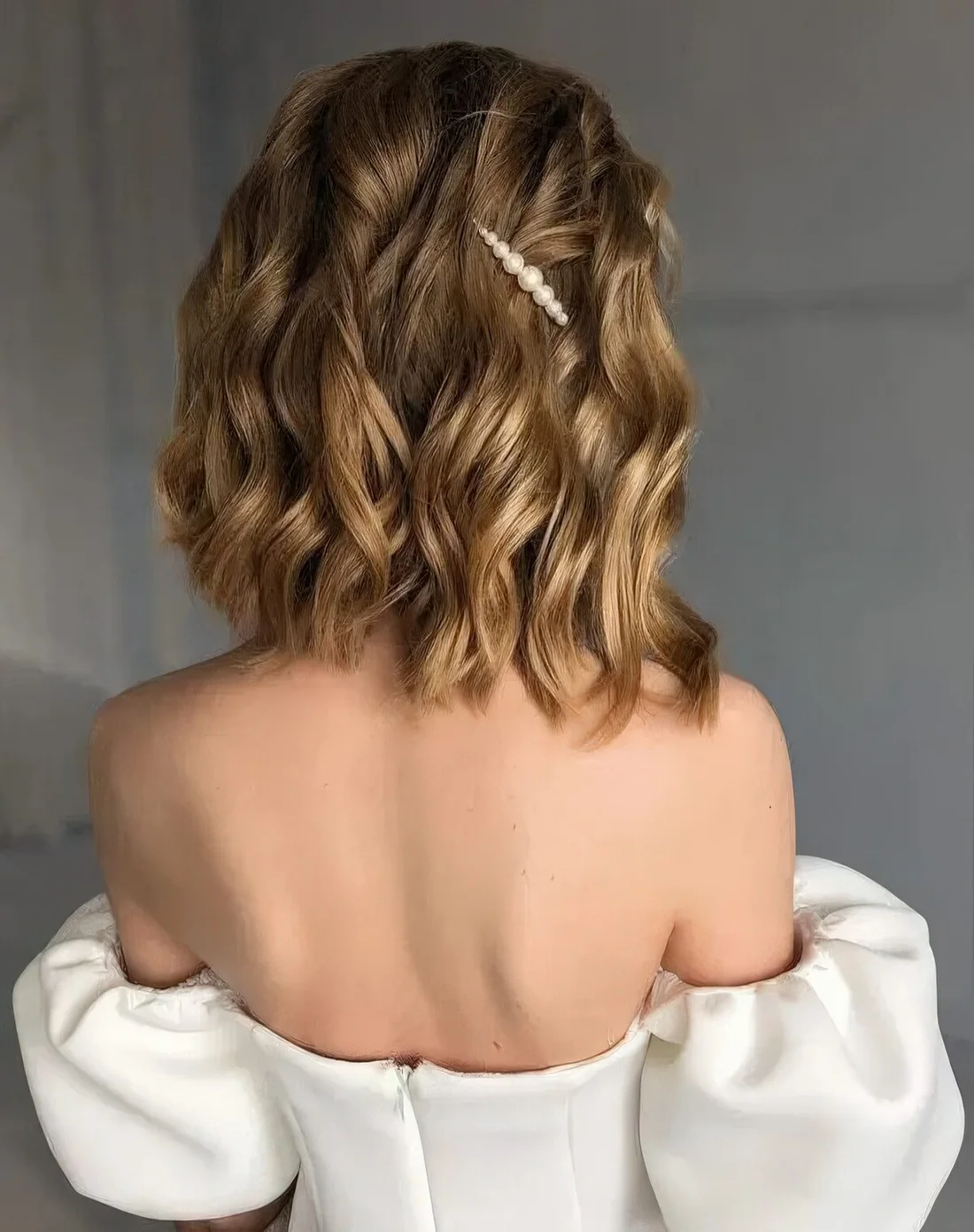 Golden blonde wavy bob with a single pearl hair pin.