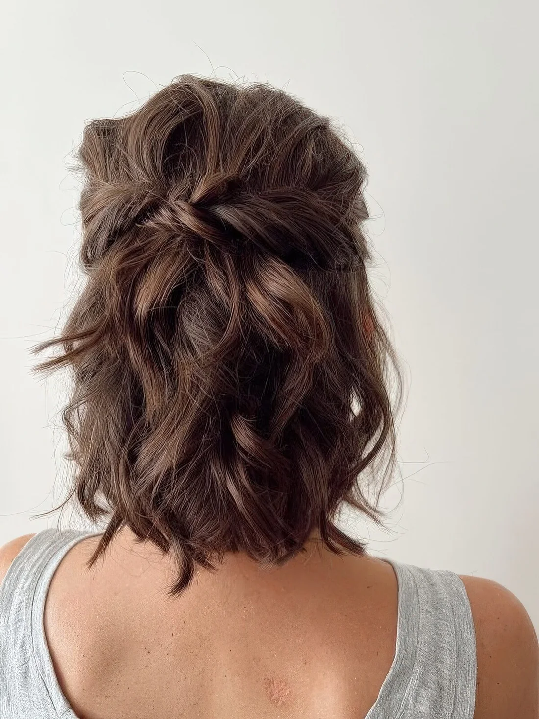 Messy twisted and wavy half updo with waves on top and waves down.