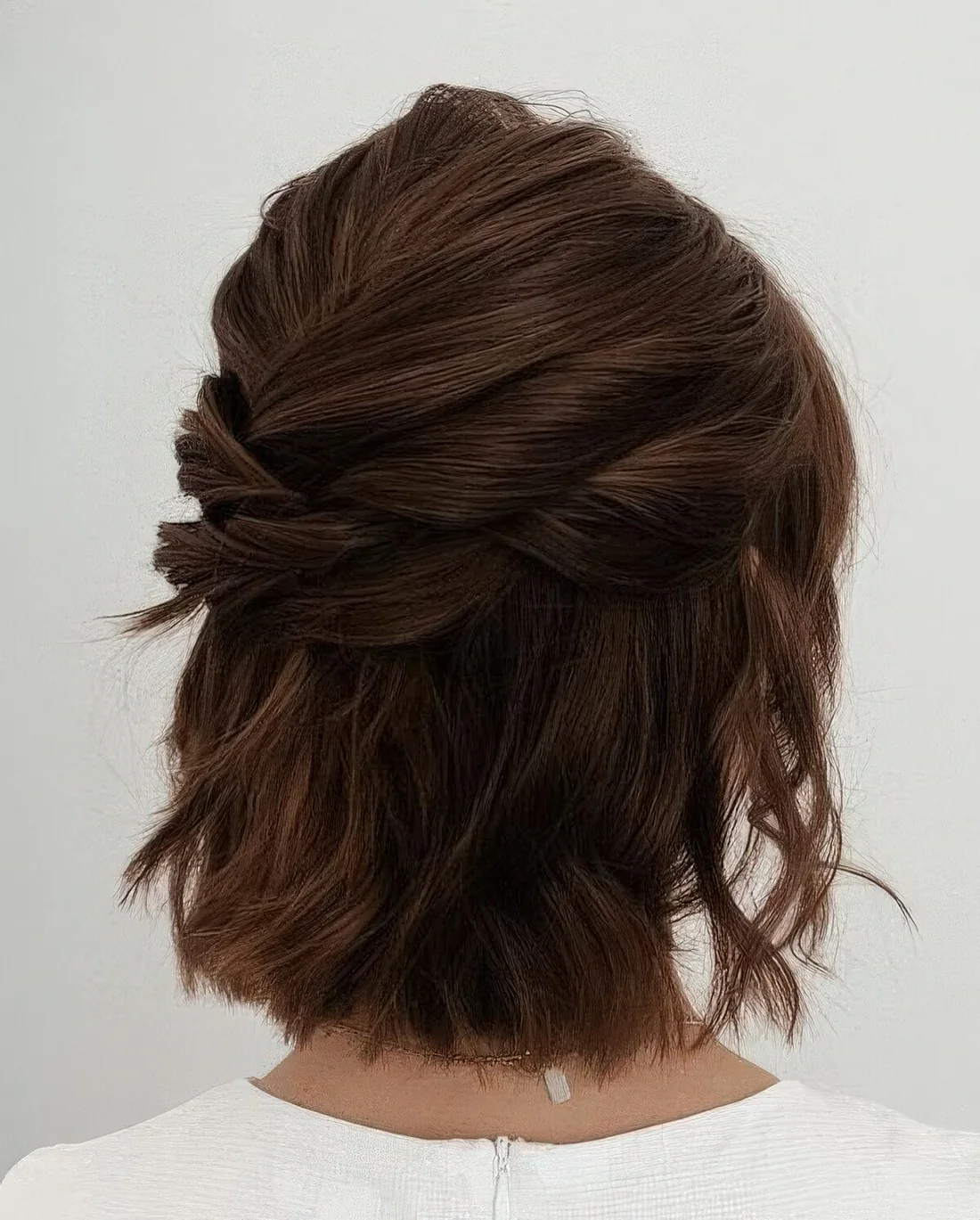 Modern half updo with several twists on top and a bump, with some waves down.