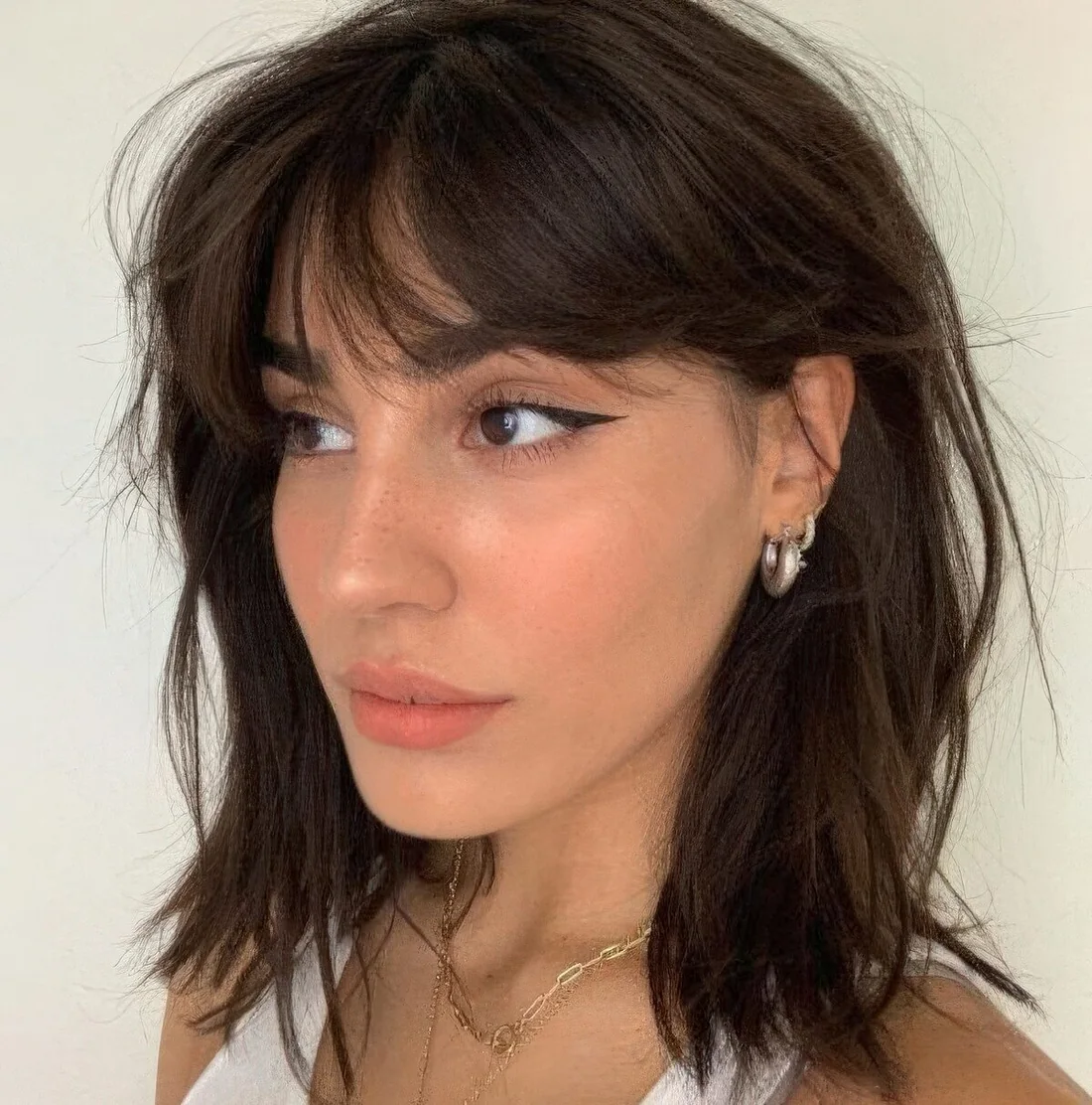 Messy dark brown collarbone bob with messy bangs and plenty of texture.