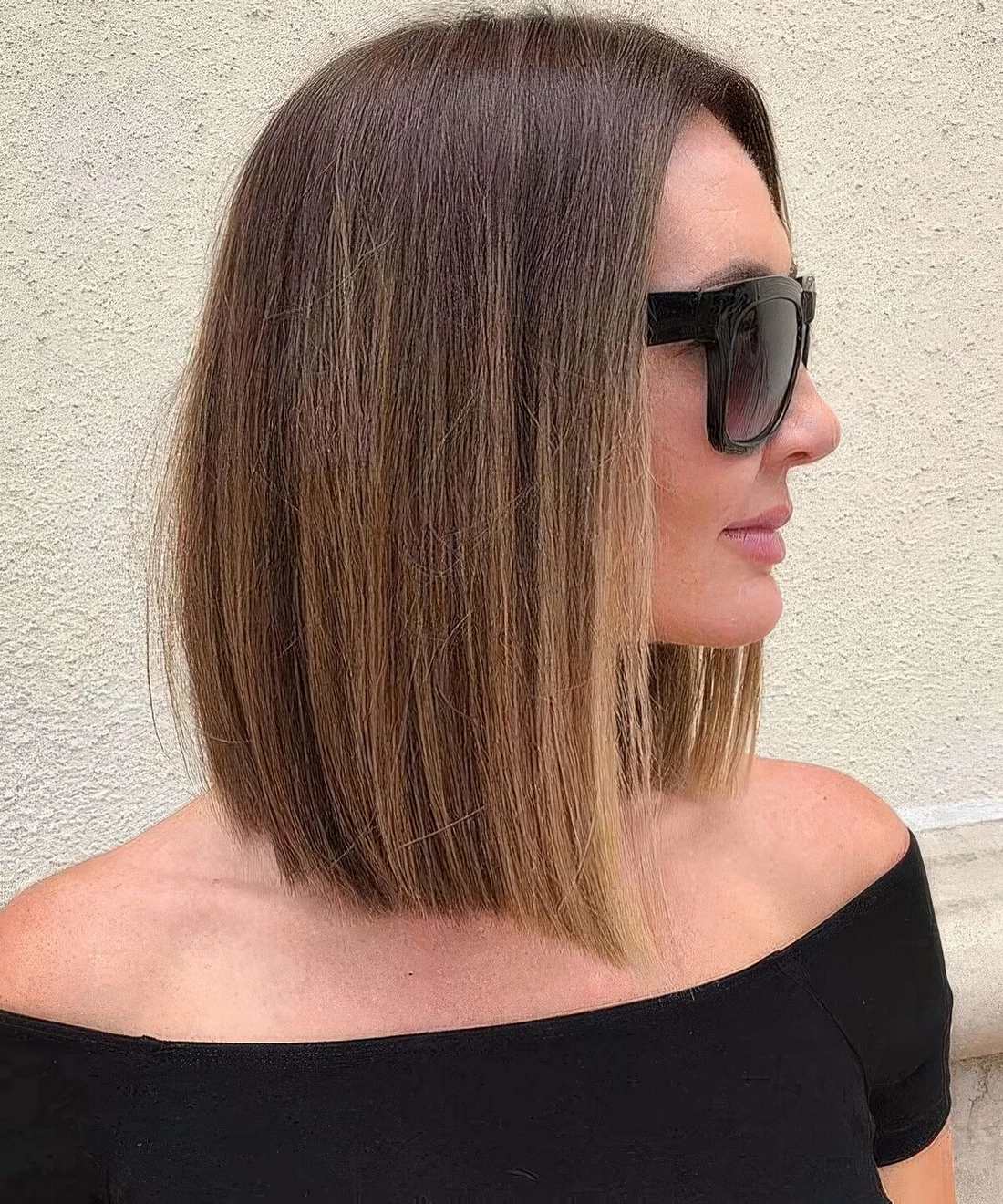 Sleek brown collarbone bob with blonde balayage and center part plus enough volume.