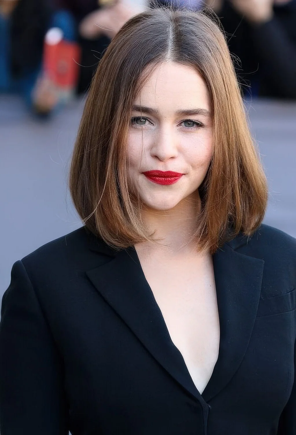 Emilia Clarke wearing a dark brunette collarbone bob with a touch of balayage and side part.