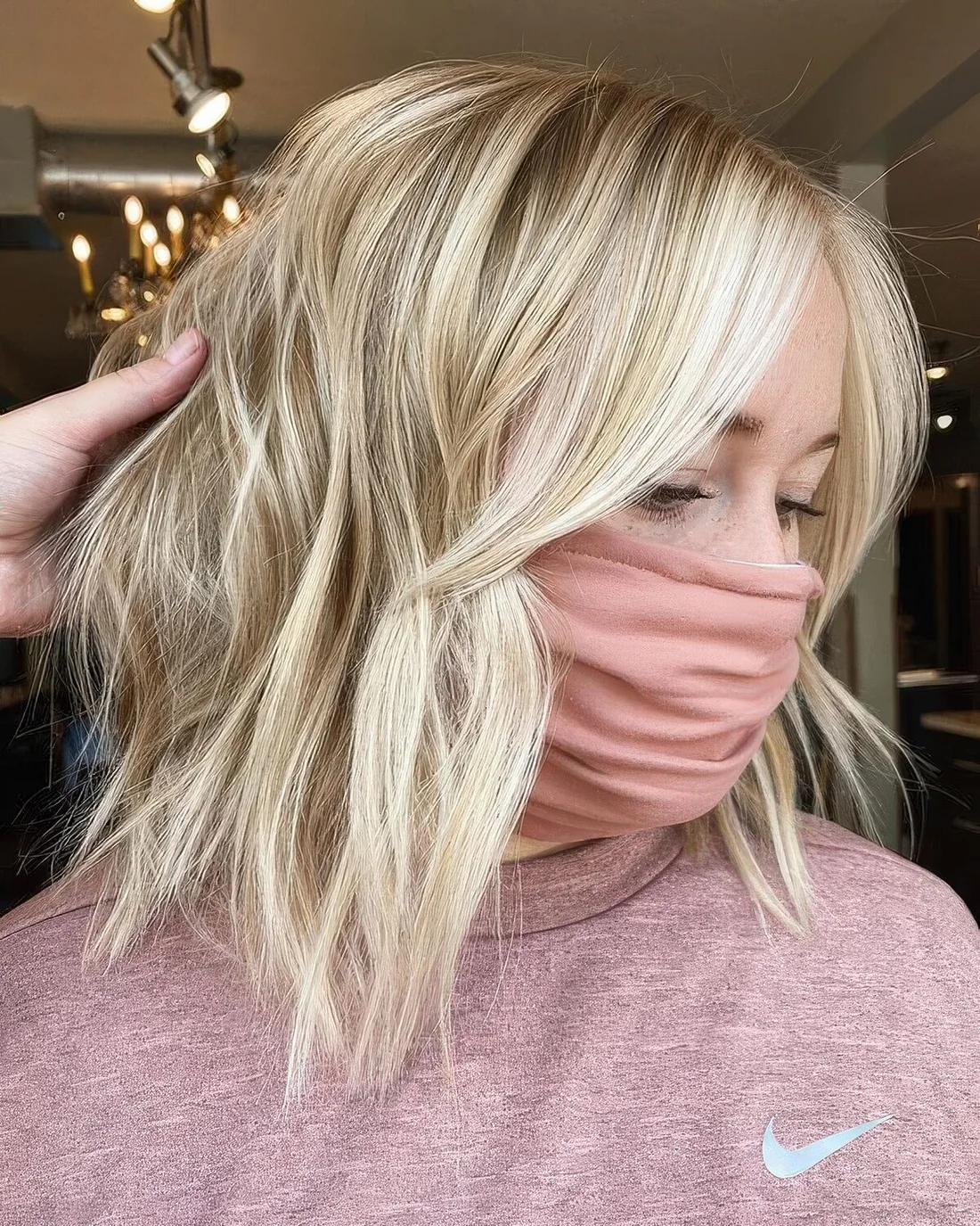 Blonde hair with icy blonde balayage, with waves and curtain bangs.