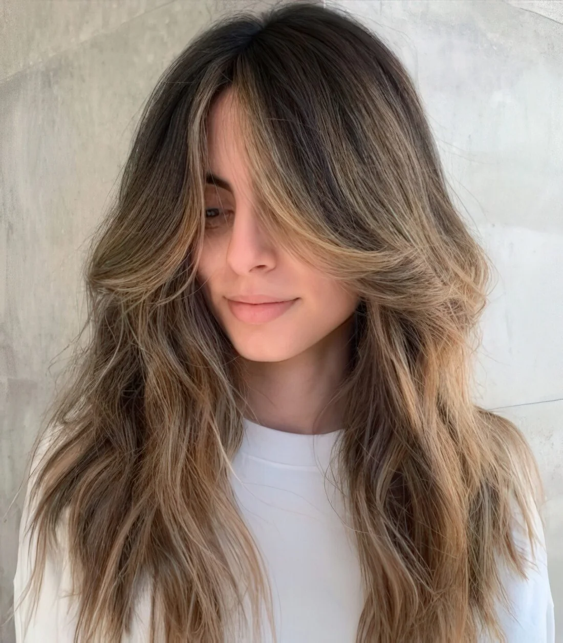 Long brunette locks with soft honey balayage and curtain bangs, with textures are incredibly beautiful.