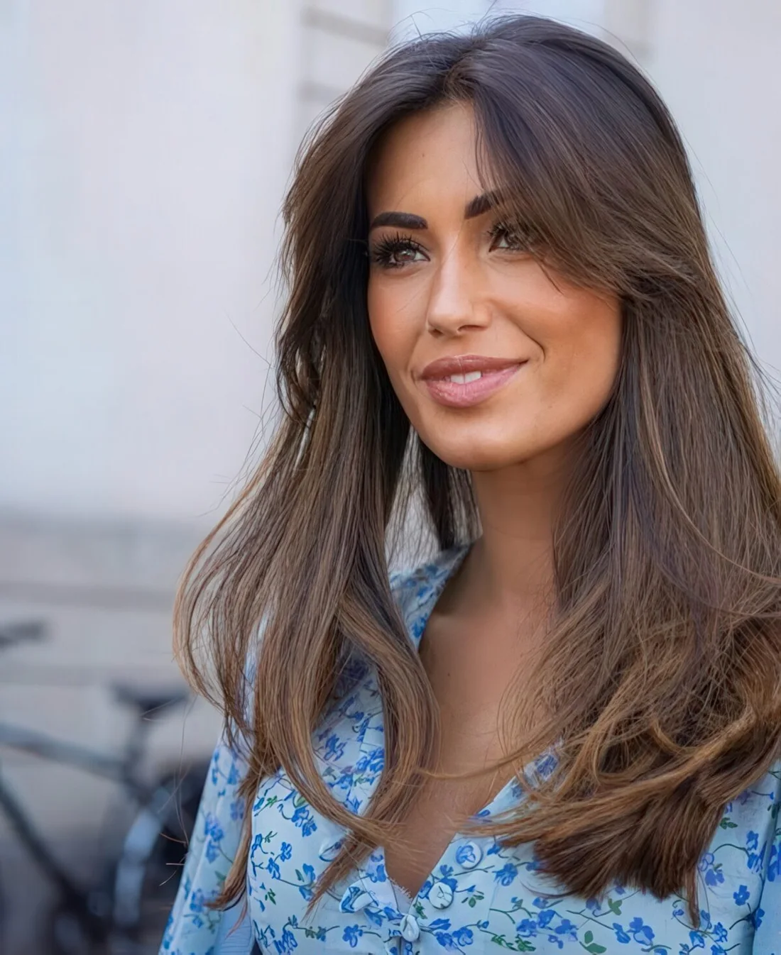 Long dark brunette hair with texture and volume, with long curtain bangs.