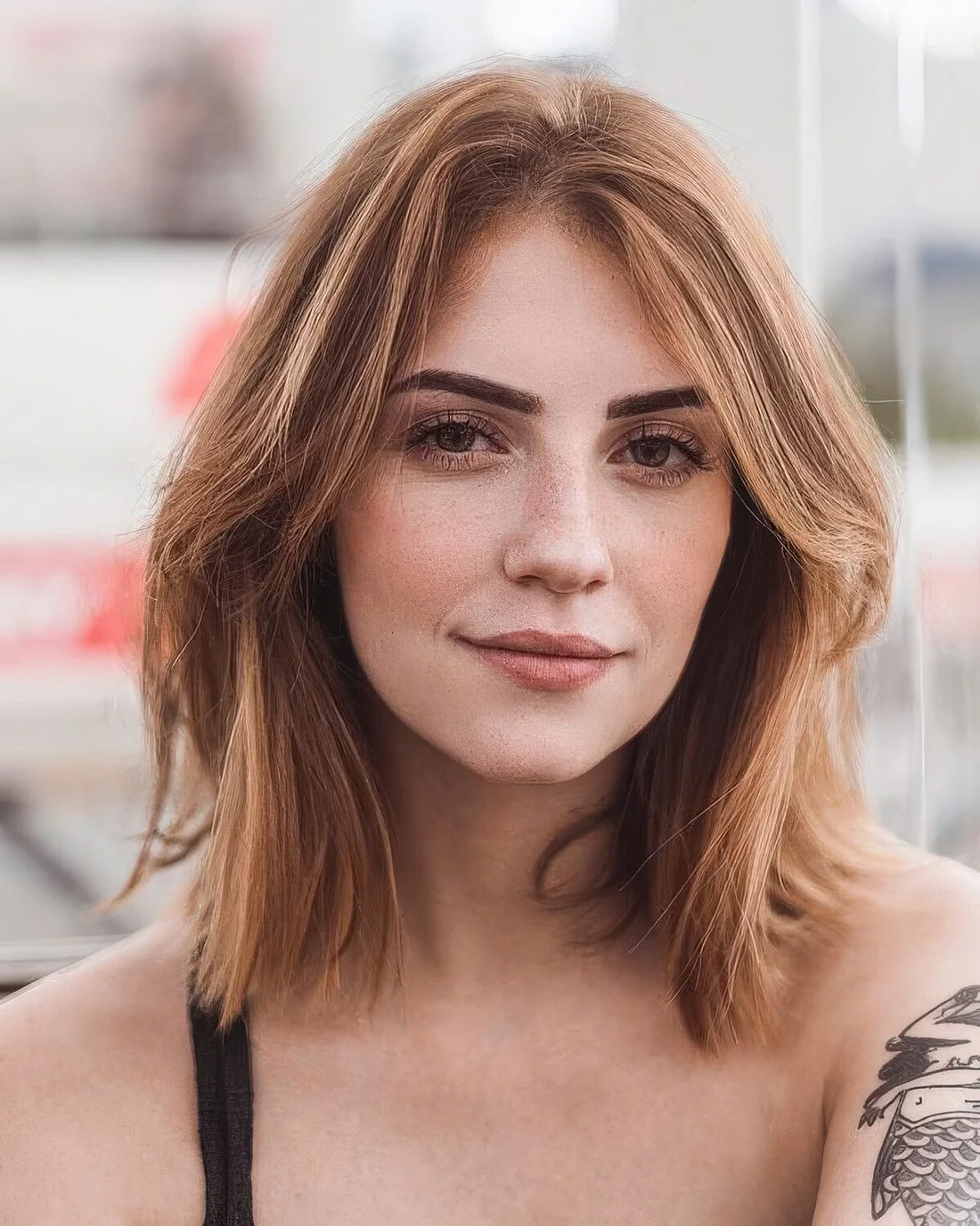 Ligth ginger medium-length hair with light blonde balayage and curtain bangs look amazing and very feminine.