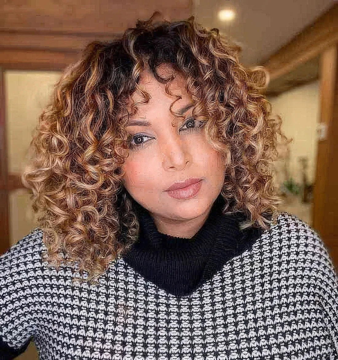 Caramel curly medium-length bob with a darker root.