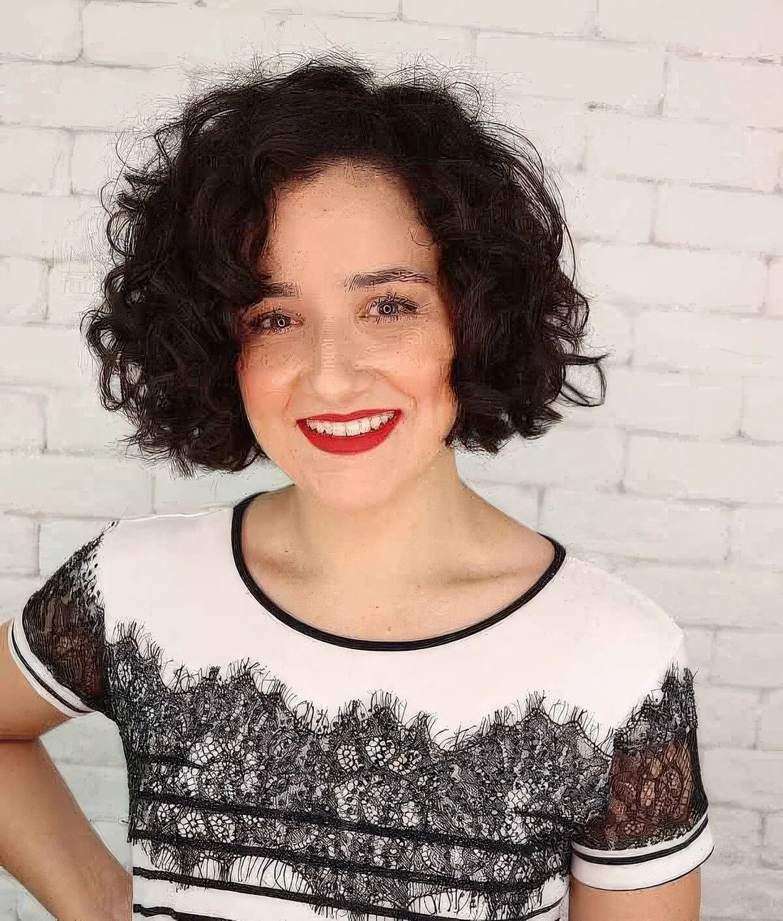 Dark brunette naturally curly bob with side bangs.