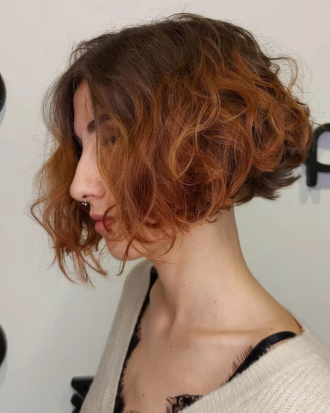 Short curly angled bob with a darker root and a ginger ombre.