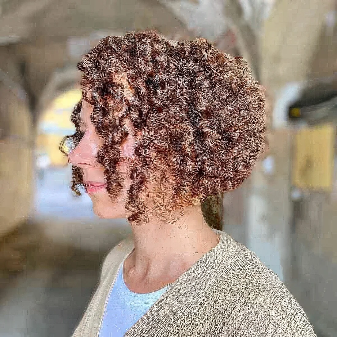 Light brunette angled curly bob allows for weight removal to help curls bounce.