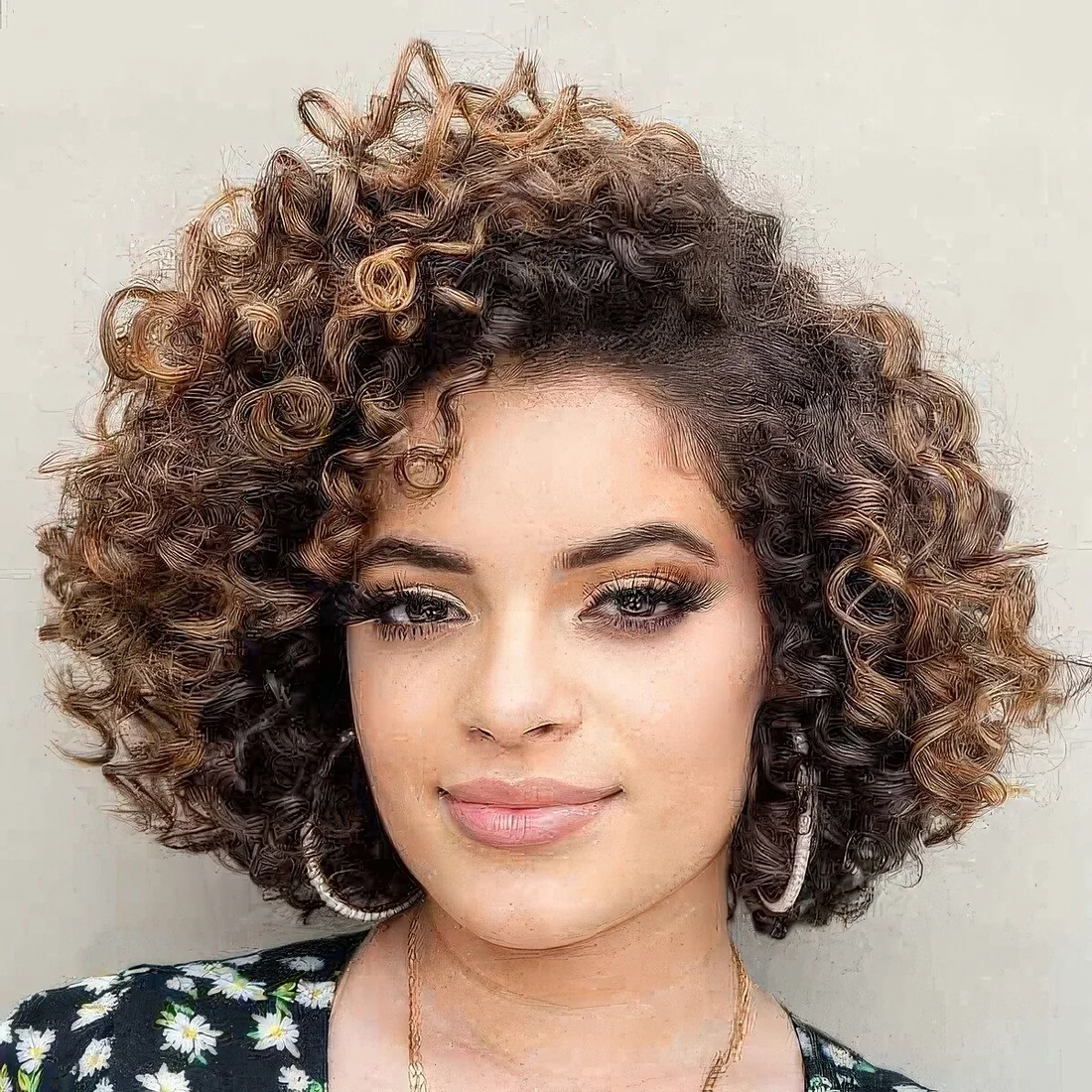 Long bob with natural curls with a darker root and caramel balayage.