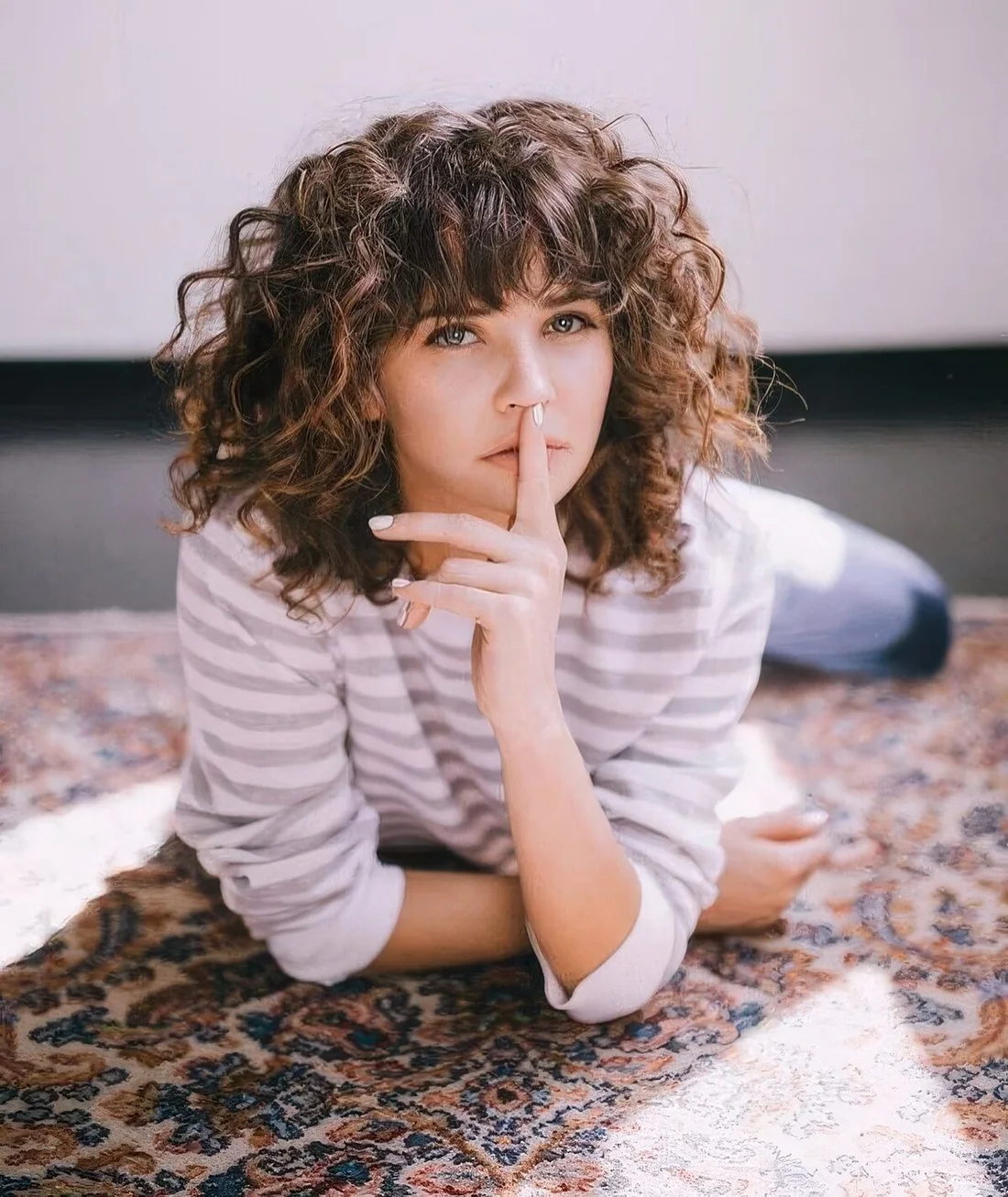 Long curly burnette bob with shorter layers in the front and short bangs.