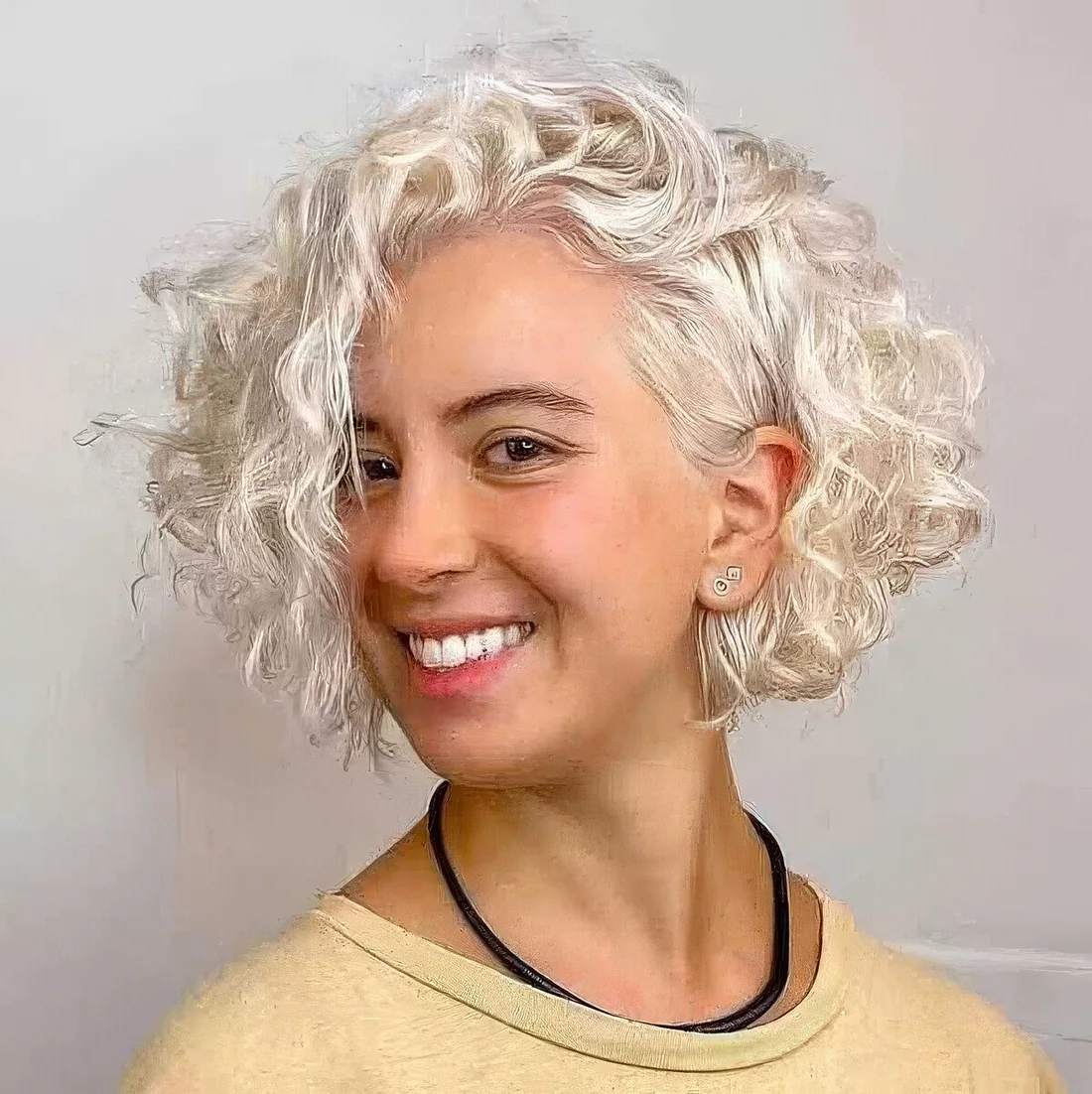 Platinum white curly chin-length bob with medium-length layers and a long side fringe.