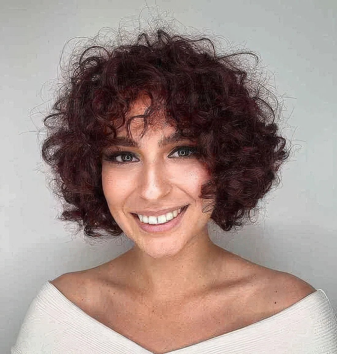 Very short burgundy to purple curly haircut with bangs.