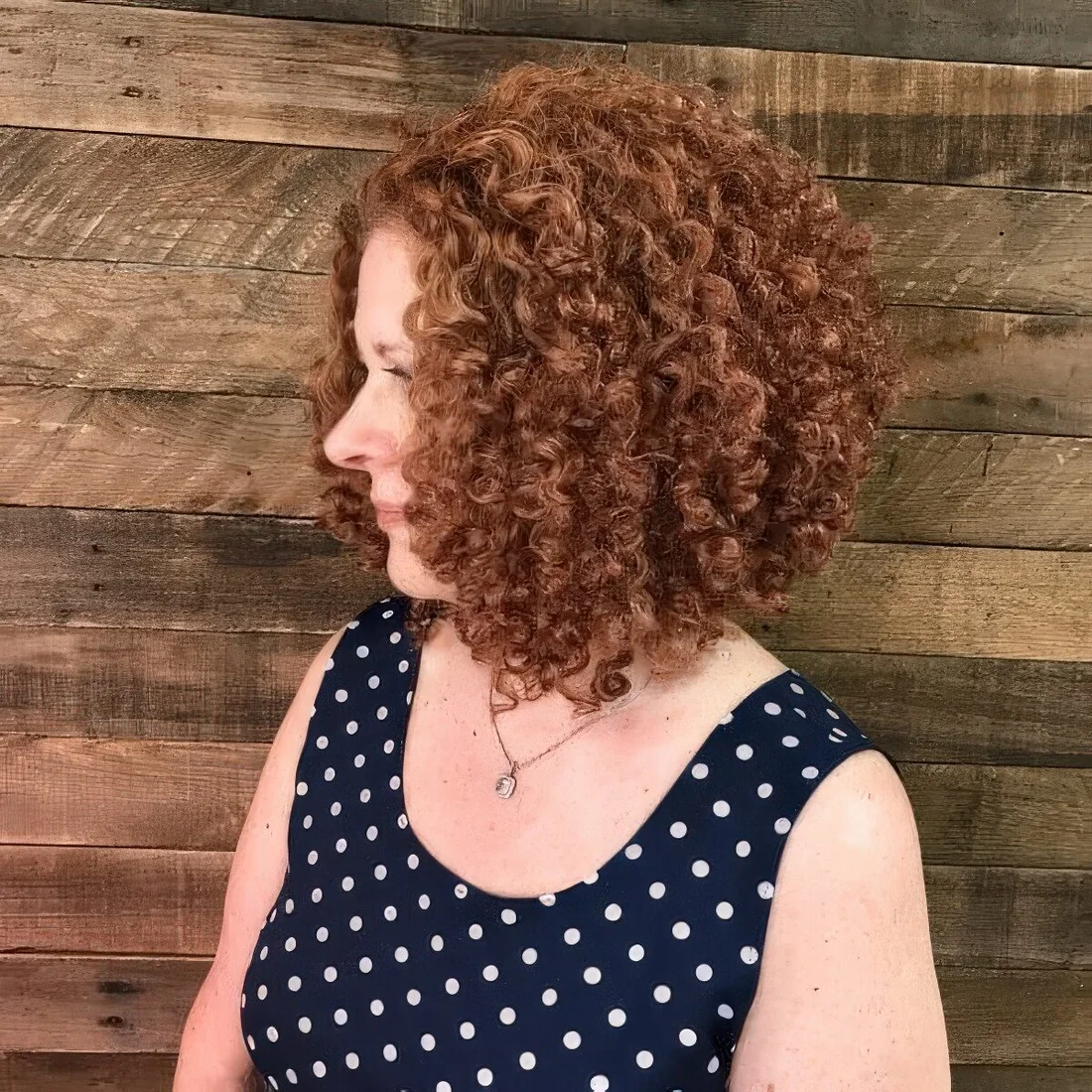 Asymmetrical curly bob in a soft brownish ginger shade.