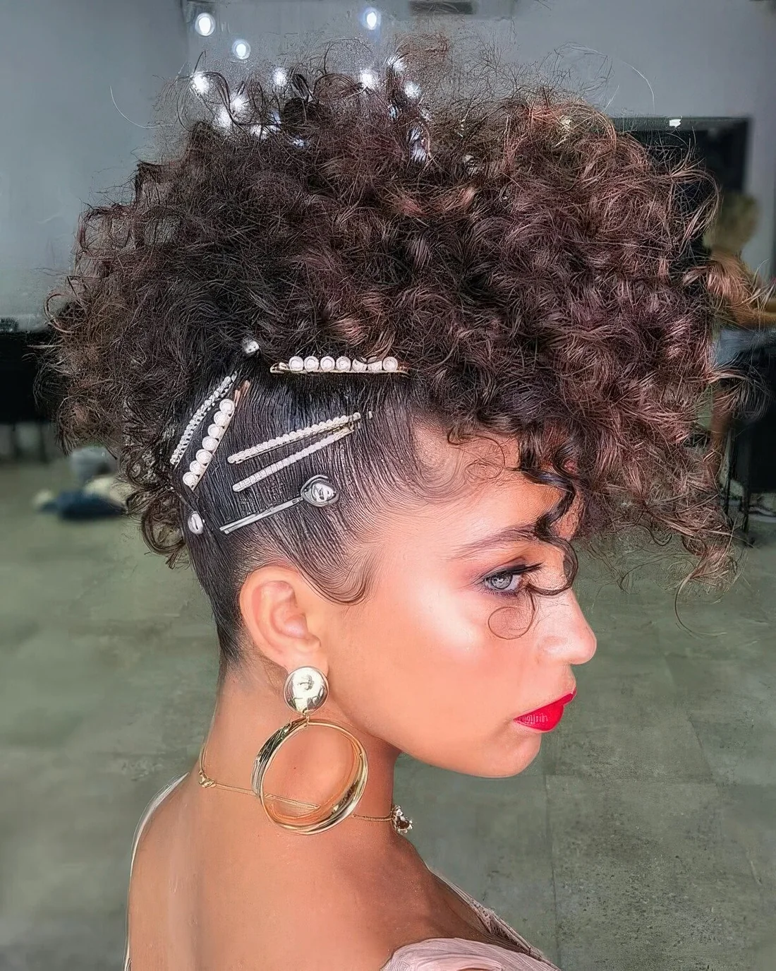 Creative faux mohawk updo with curls and a whole arrangement of hair pins with pearls.