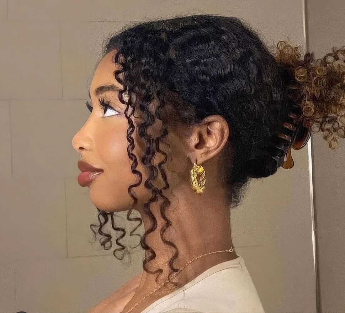 Casual updo with curls secured with a claw clip and some curls framing the face.
