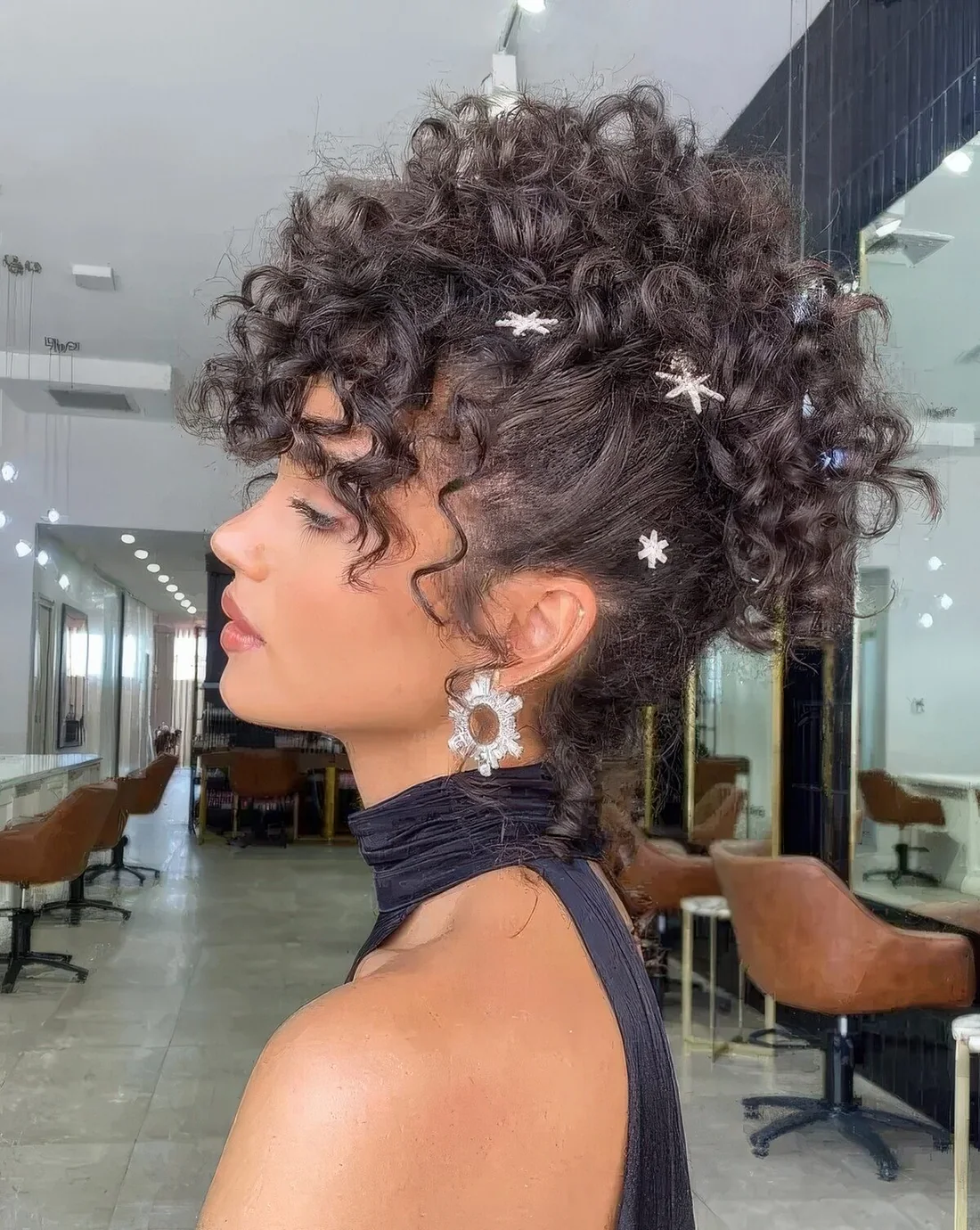 Curly mohawk updo with curls on top and some shiny rhinestone hair pins all over the head.