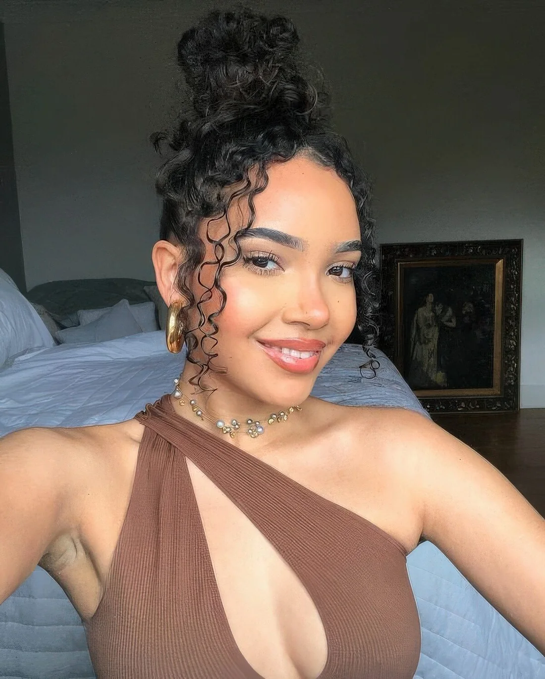 Party worthy hairdo with a messy top knot, a curly top and face-framing hair.