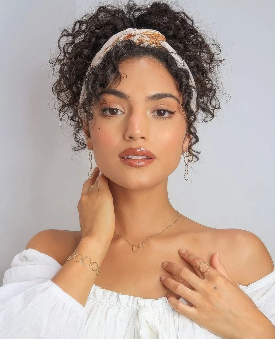 High curly hairdo, a headband and curls framing the face are a chic look with a retro vibe.