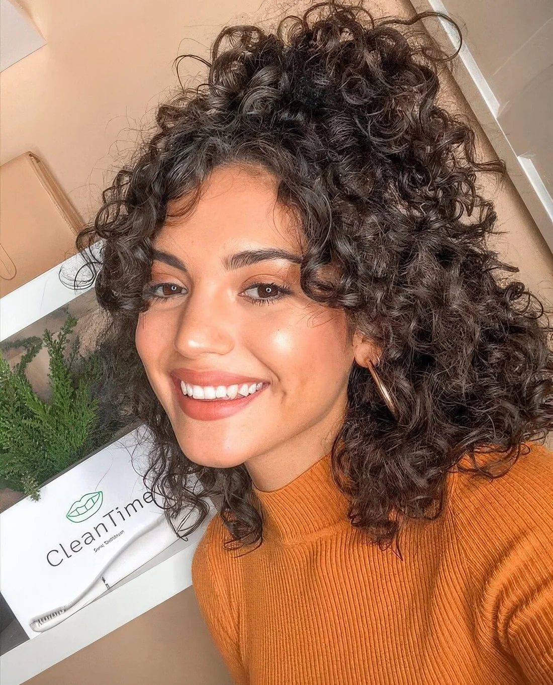 Medium half updo with a high ponytail, curls and face-framing bangs.