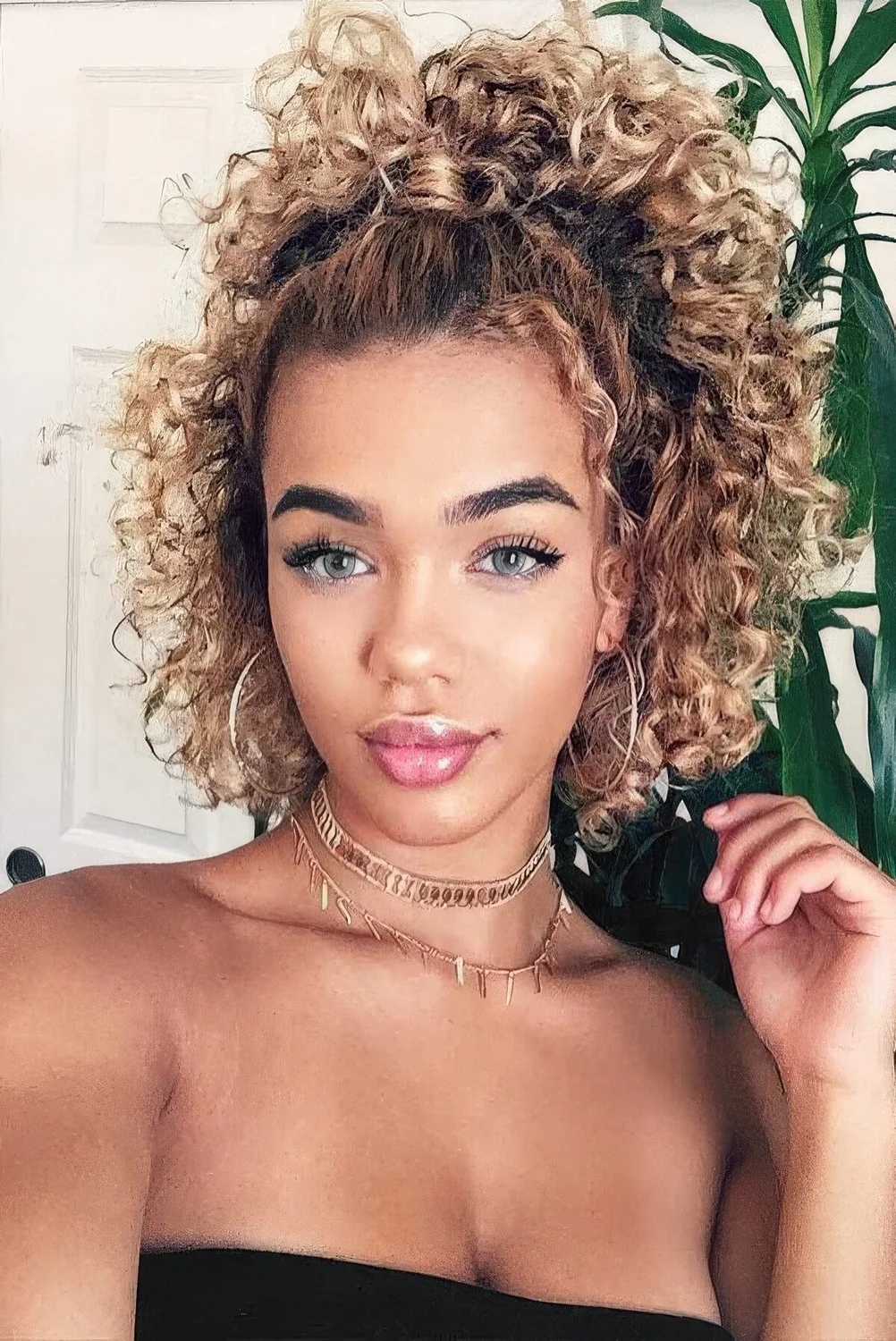 Half-up hairstyle with a high ponytail and curls down.