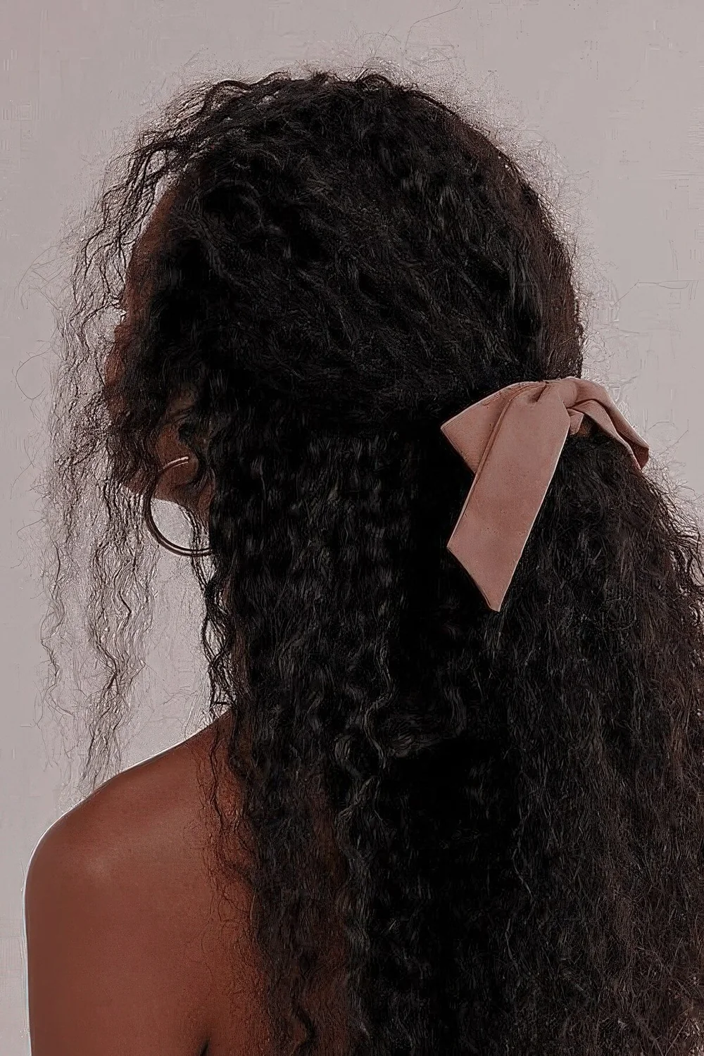 Long and volumetric curly hair styled as a half updo and done with a ponytail.