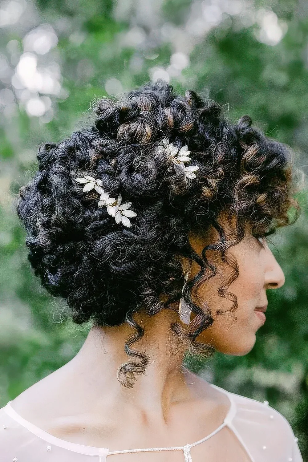 Curly half updo with floral hairpieces and curls down.