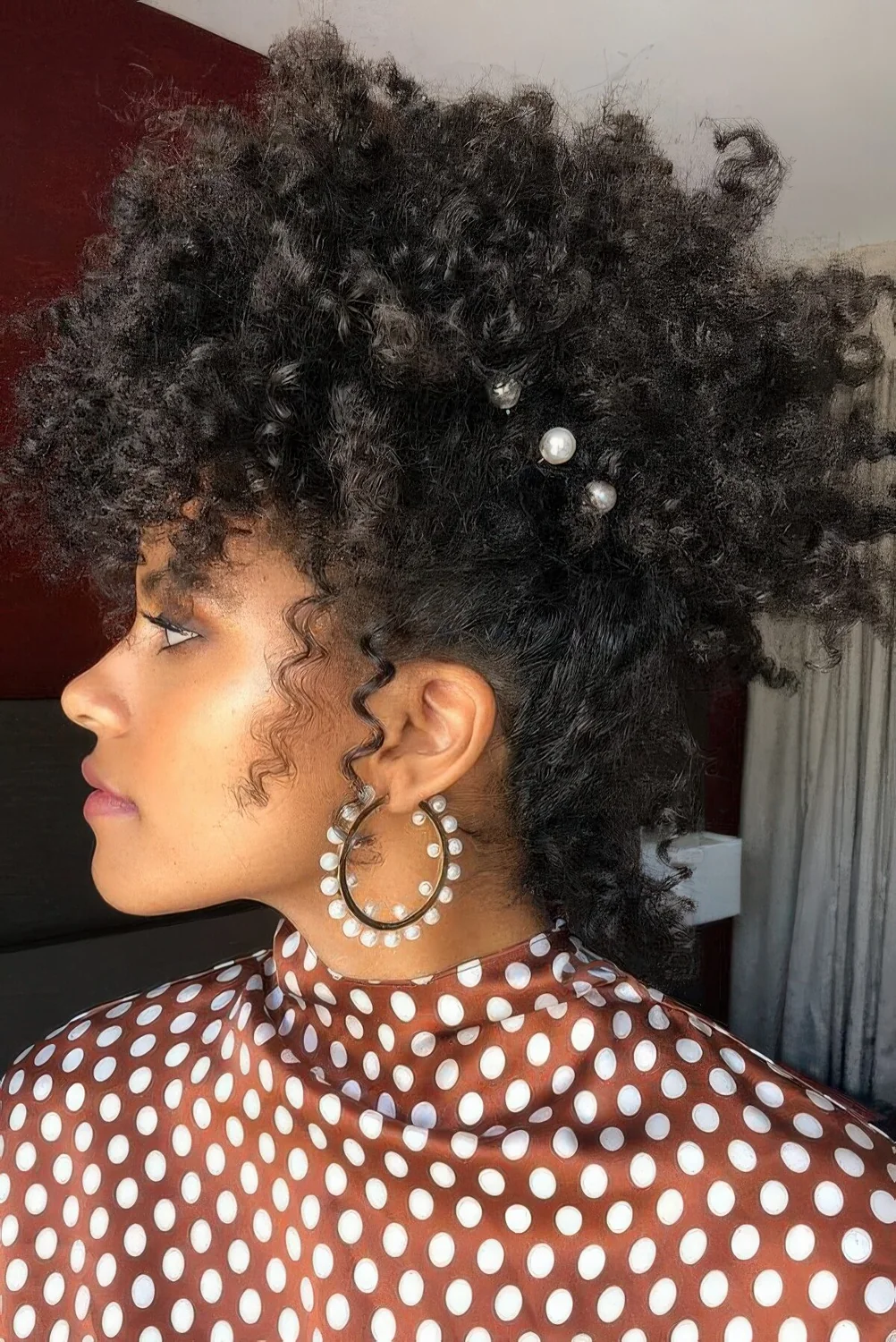 Curly updo with pearl hair pins and some locks down to frame the face.