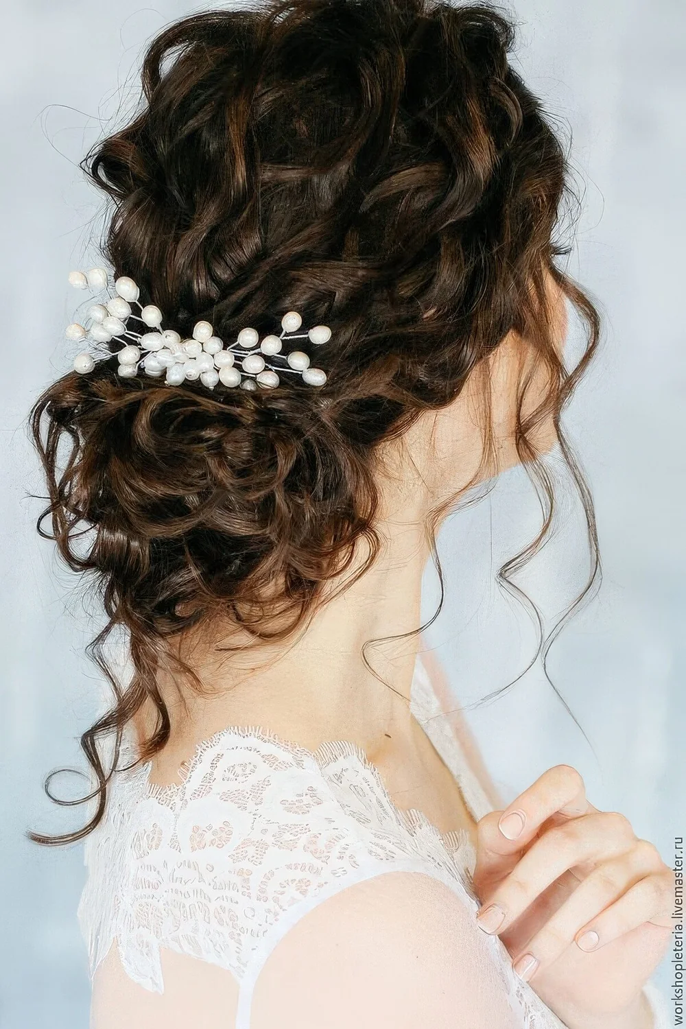 Chic and cool curly low bun with curls on top and down to frame the face, a large pearl hair pin for an accent.