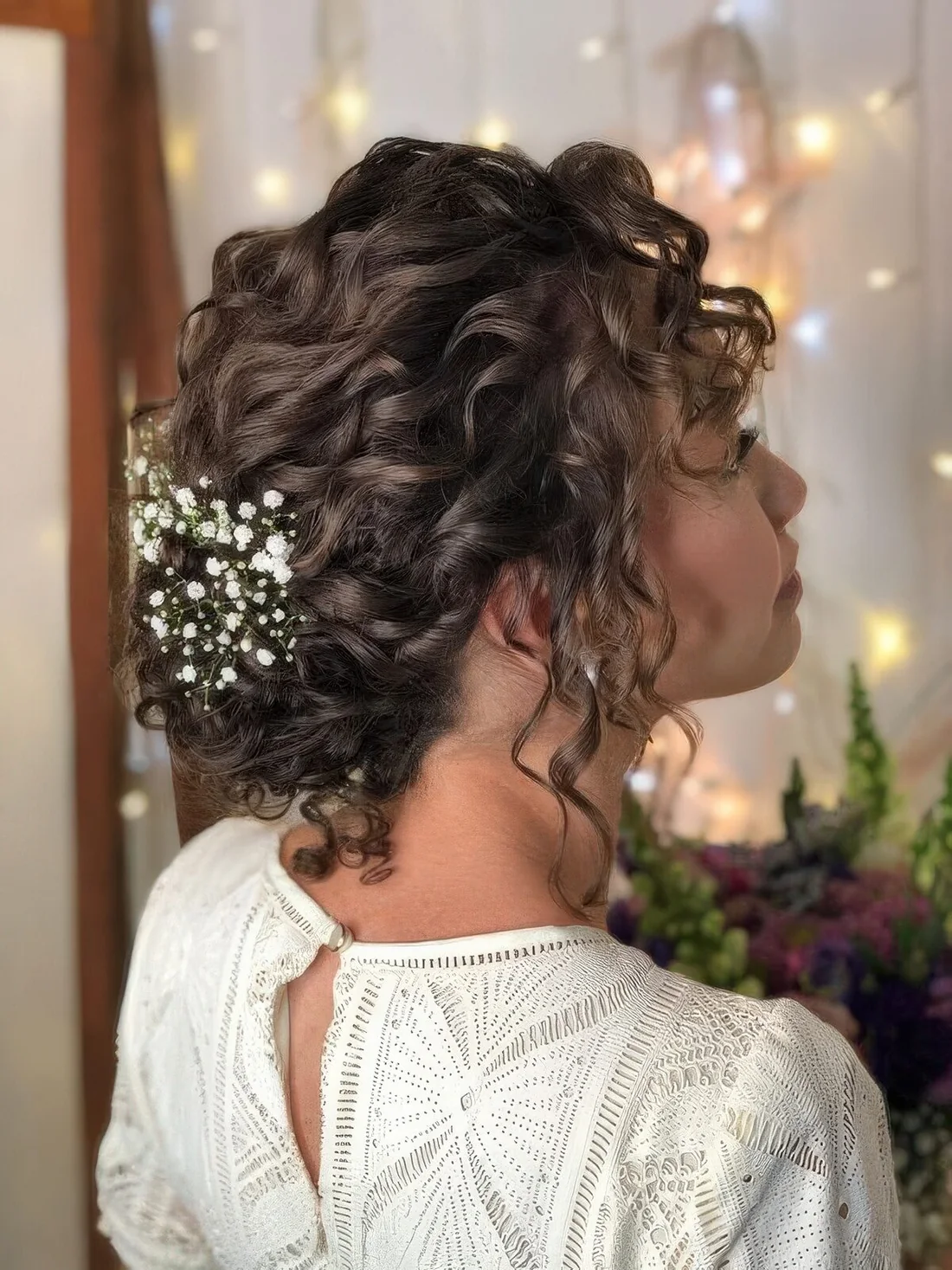Curly low updo with curls down and baby's breath.
