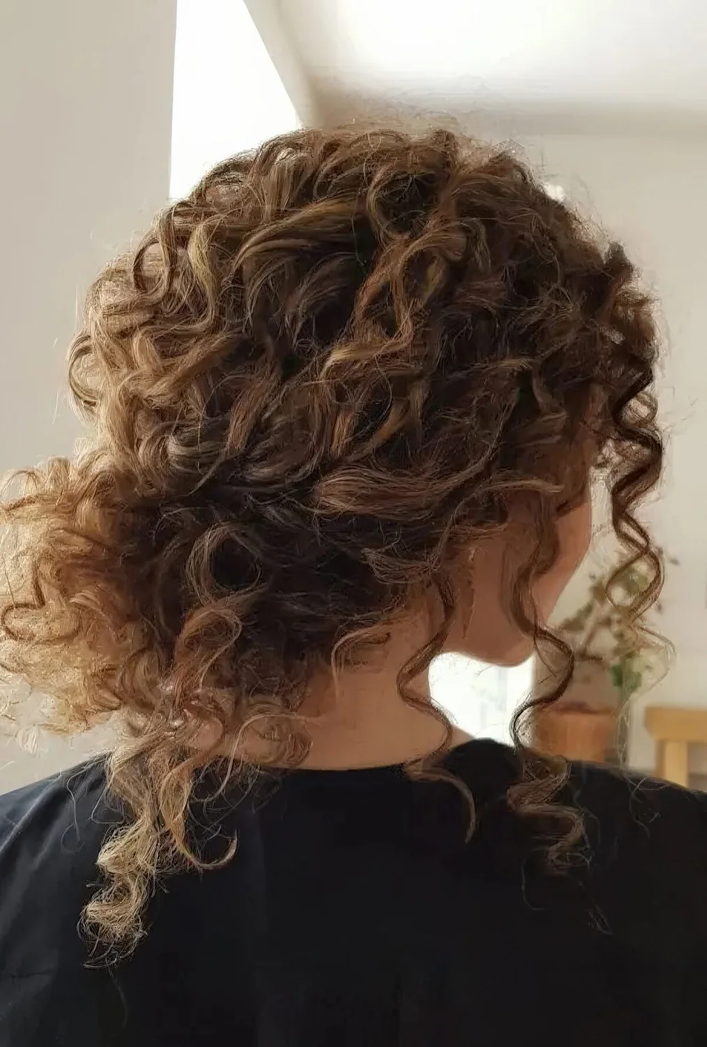 Photo showing curly messy low bun with bangs, with the hairstyle clearly visible.