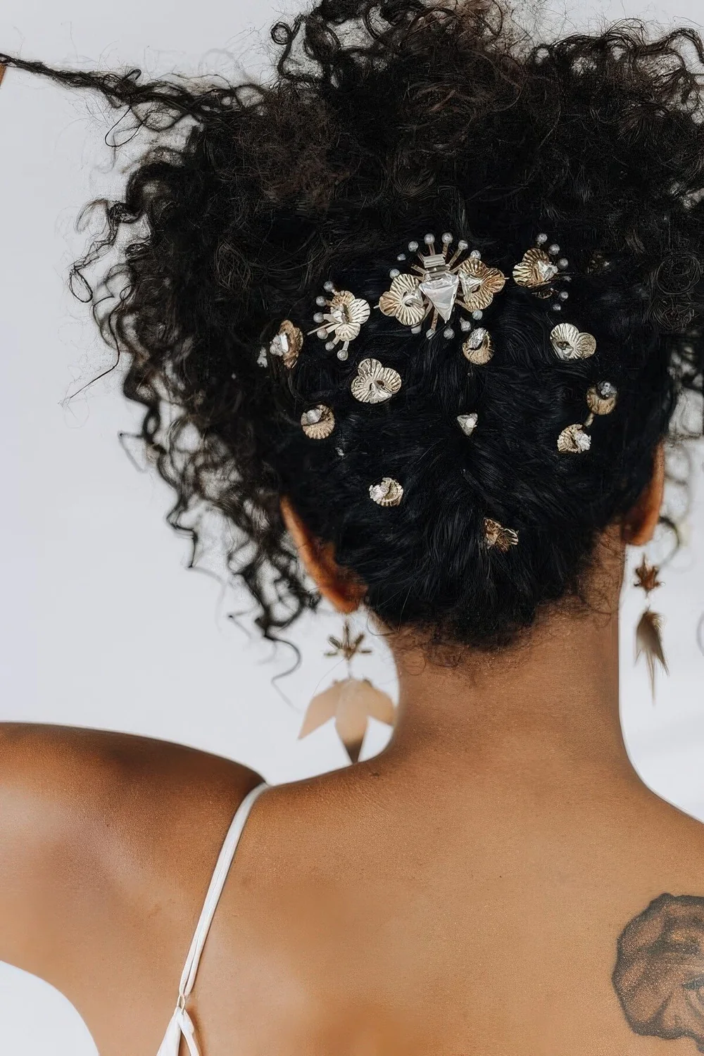 Curly wedding updo with lots of rhinestone hair pins to accent it and curls on top.