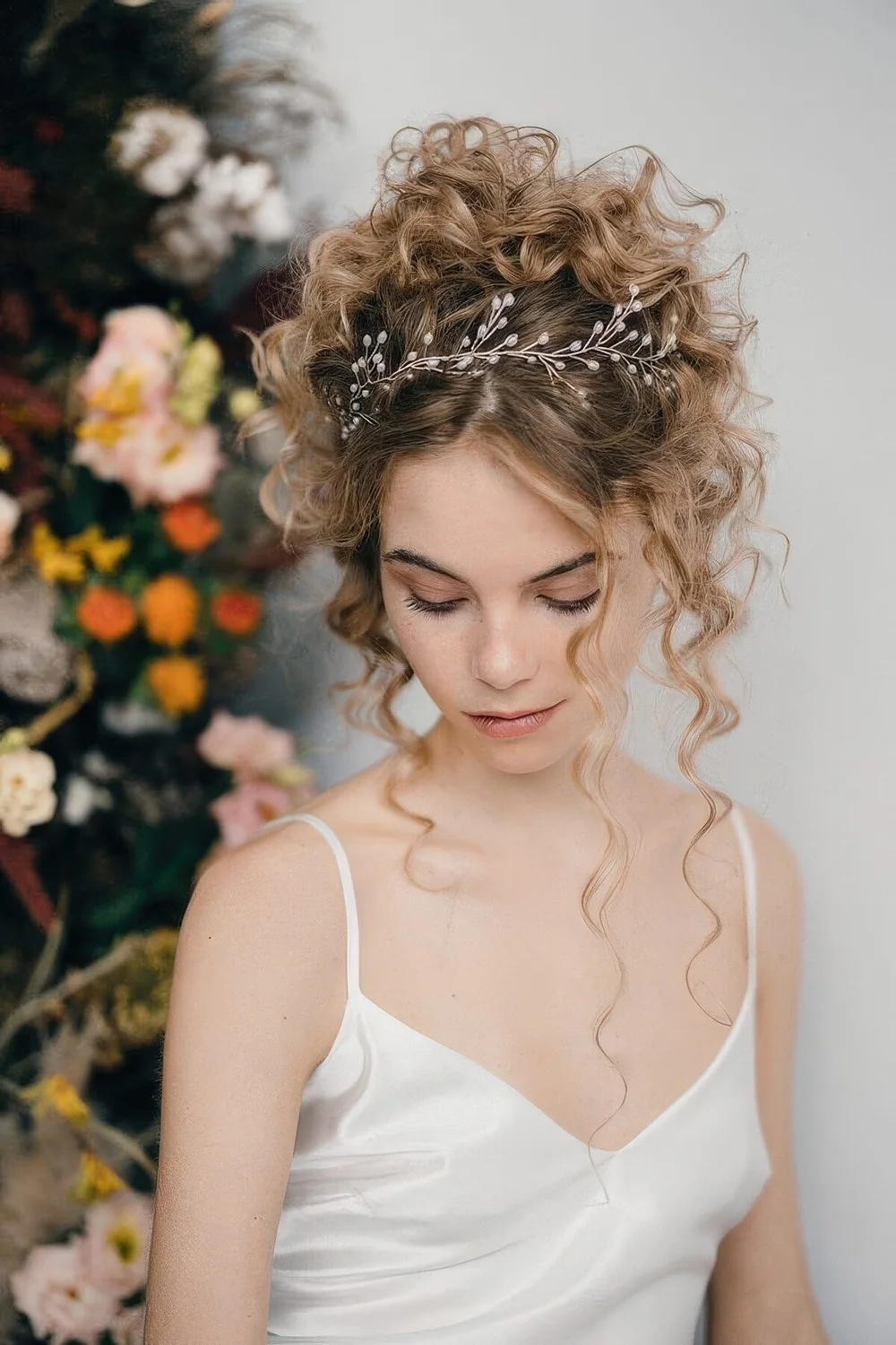 Curly updo with some curls down accented with a hair vine.