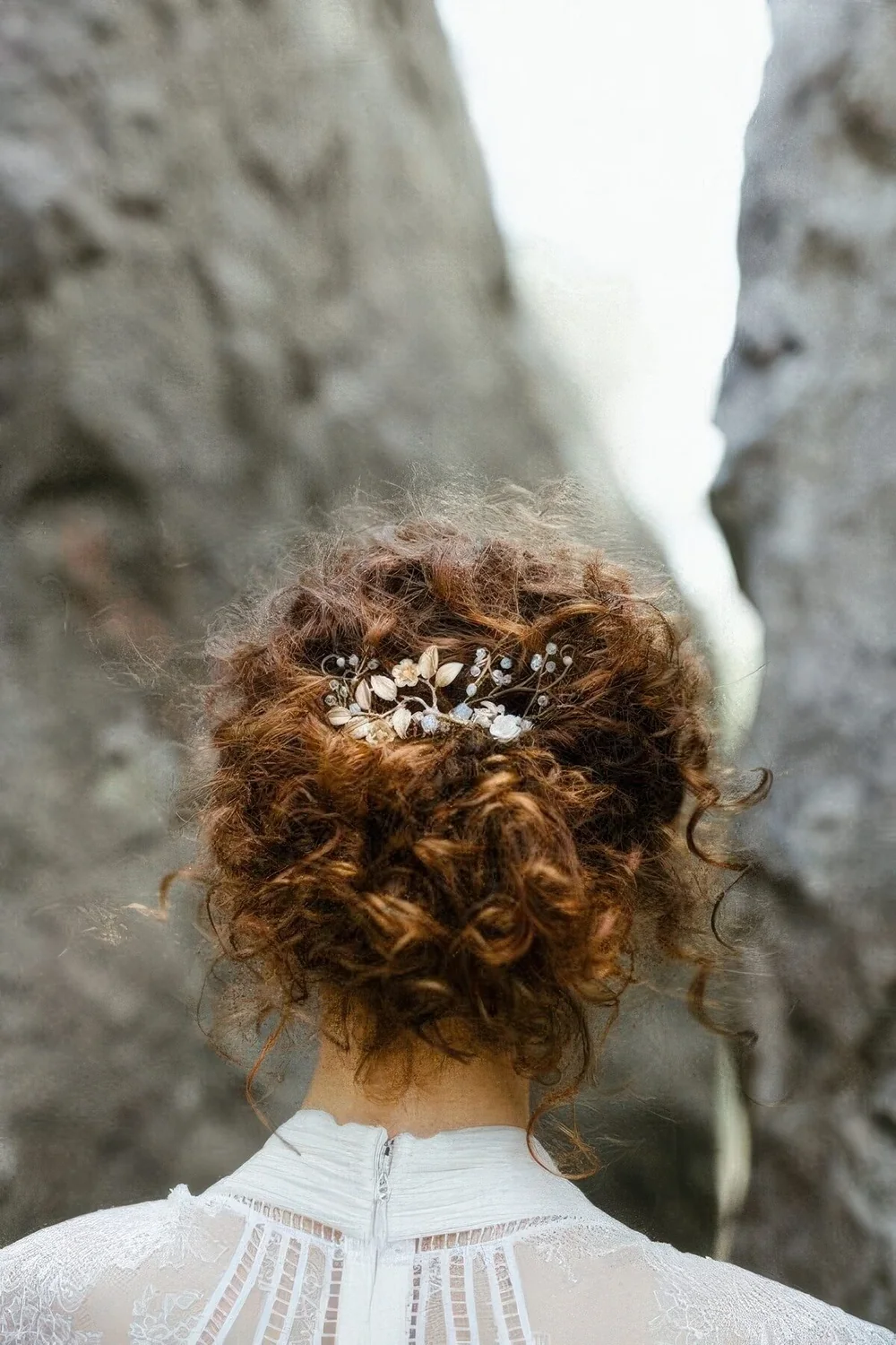 Messy curly updo with a curly top and curls down plus a rhinestone and pearl hairpiece.