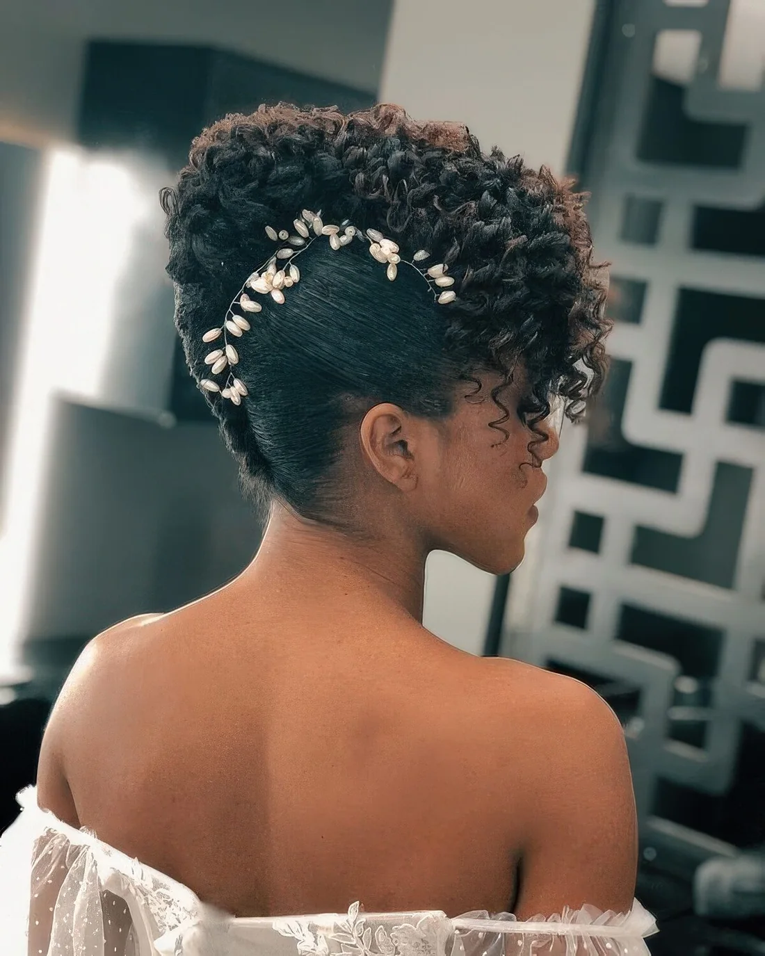 Sophisticated curly updo with curls on top and a pearl hair vine accenting the face.